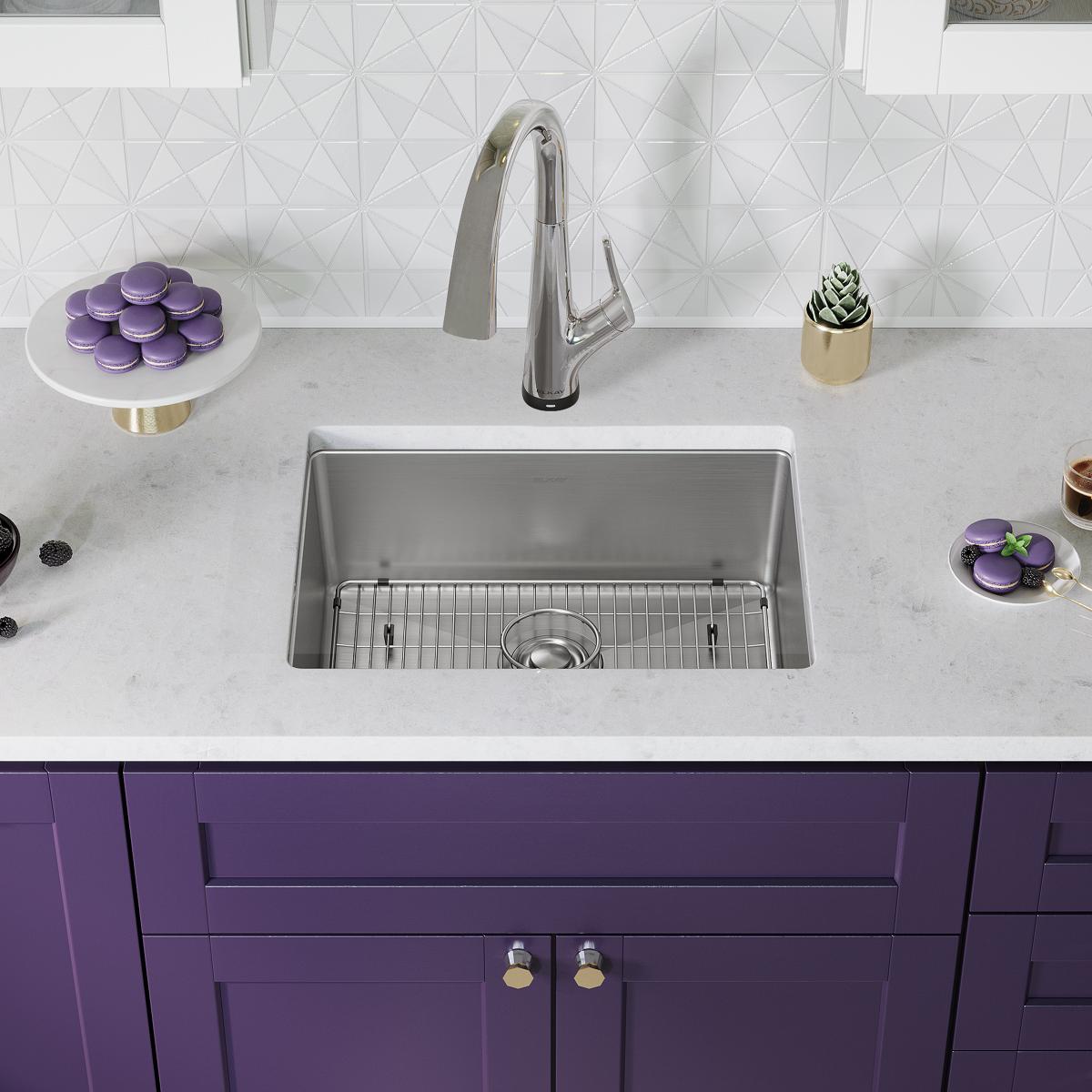 Stainless steel undermount sink with single bowl, grid strainer, and chrome pull-down faucet installed in white countertop ab