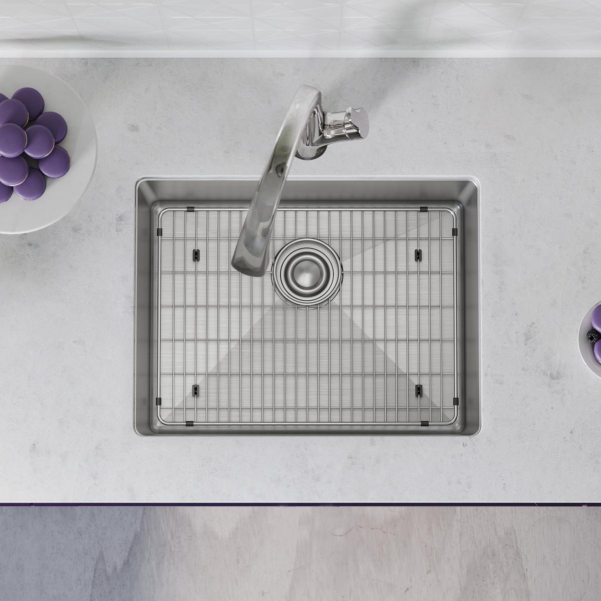 Stainless steel single bowl undermount sink with grid rack and curved filtered faucet installed in marble countertop.