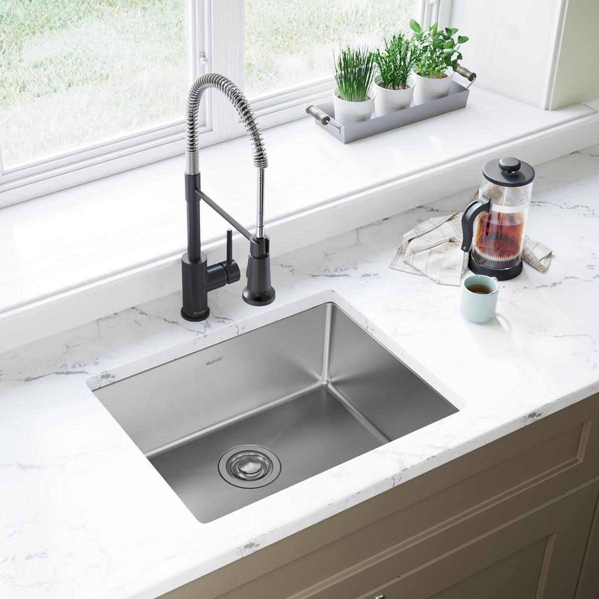 Stainless steel single bowl undermount sink installed in marble countertop with black pull-down faucet.
