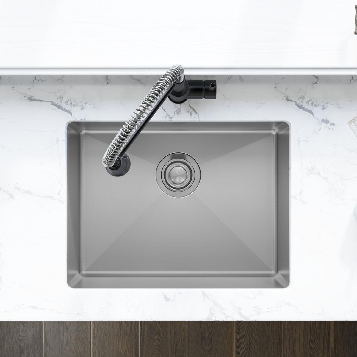 Stainless steel undermount sink with single rectangular bowl and drain, installed beneath marble countertop with flexible fau