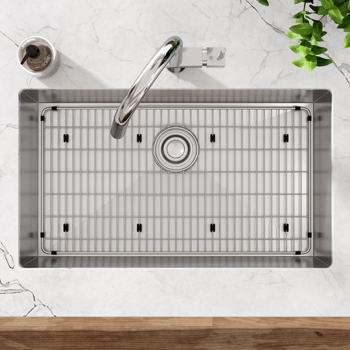Stainless steel undermount sink with rounded bowl, grid bottom, drain, and chrome faucet installed in marble countertop.