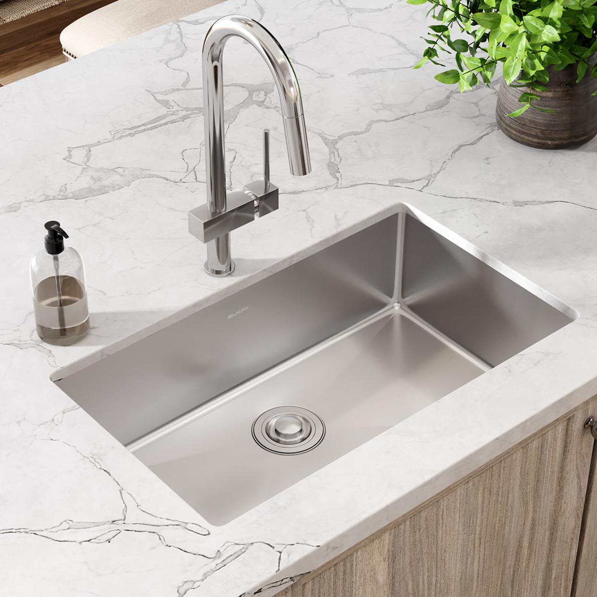 Stainless steel undermount sink with single bowl installed in marble countertop, paired with chrome faucet.