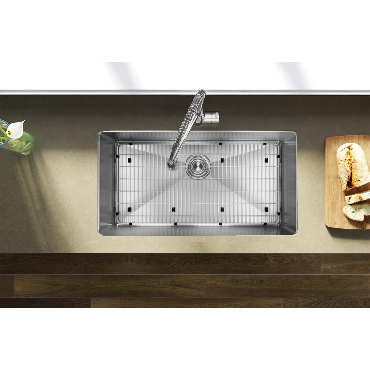 Stainless steel undermount sink with single bowl, drain fixture, and grid insert installed in countertop.