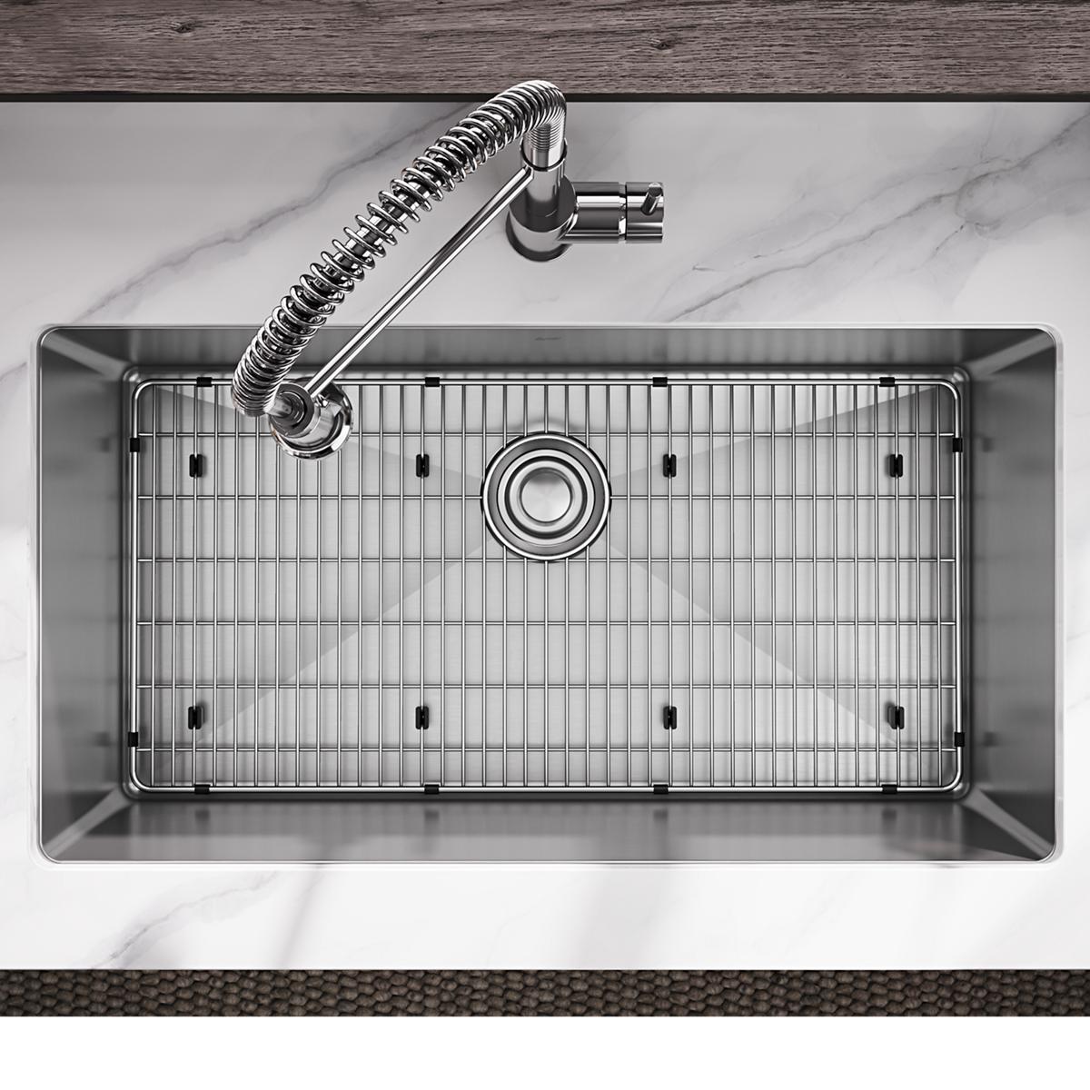 Stainless steel undermount sink with single bowl, grid insert, and curved pull-down faucet mounted on marble countertop.