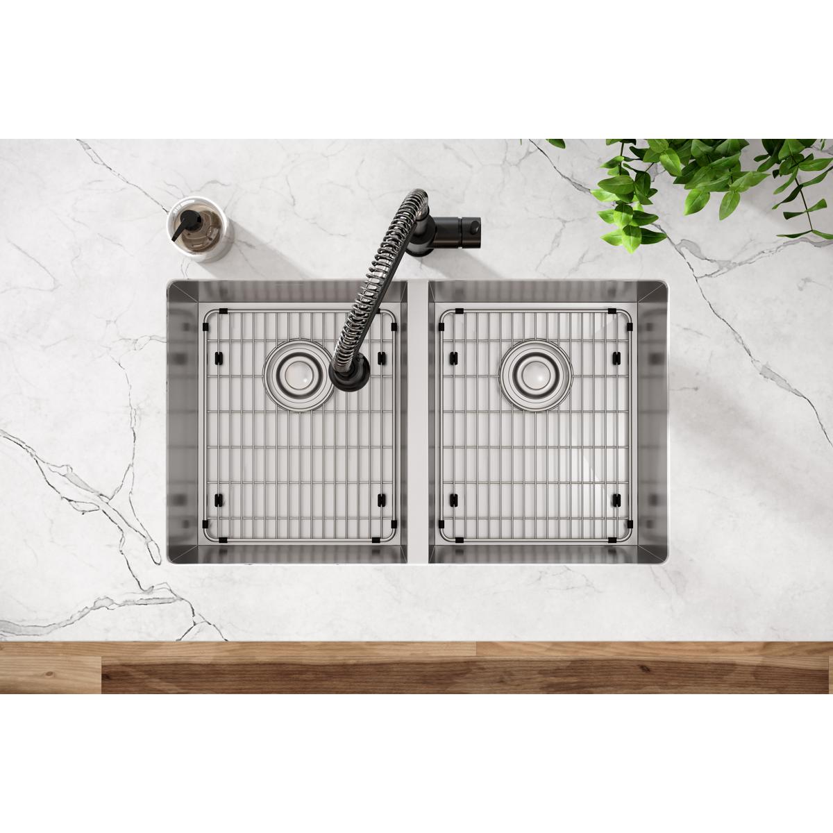 Stainless steel double bowl undermount sink with rounded corners, grid inserts, and black flexible faucet installed in marble