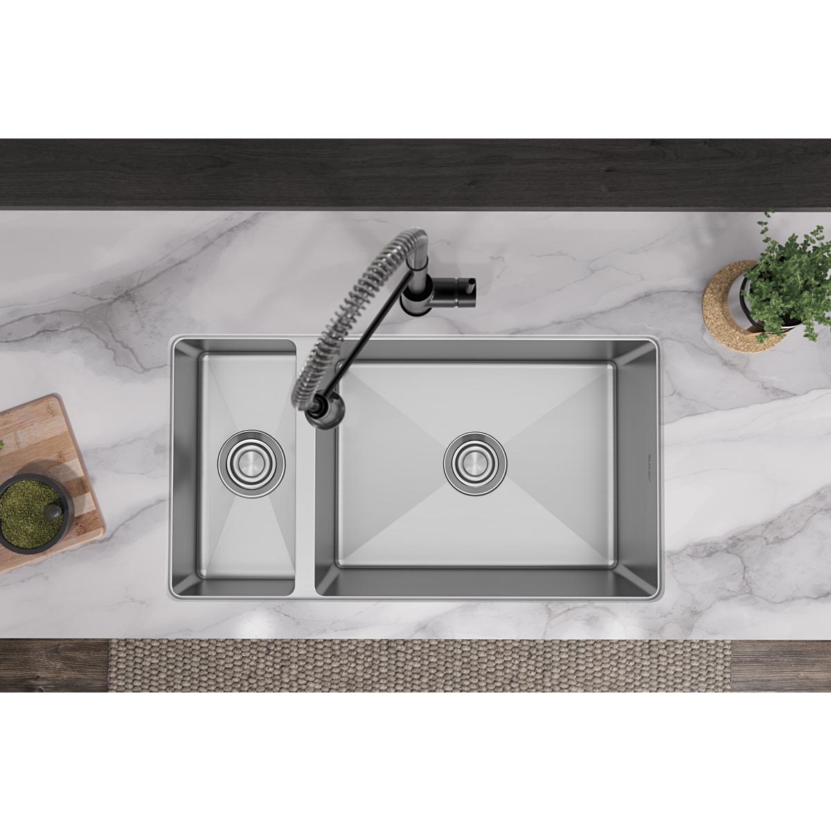 Stainless steel double bowl undermount sink with smaller left bowl and larger right bowl, installed in marble countertop with