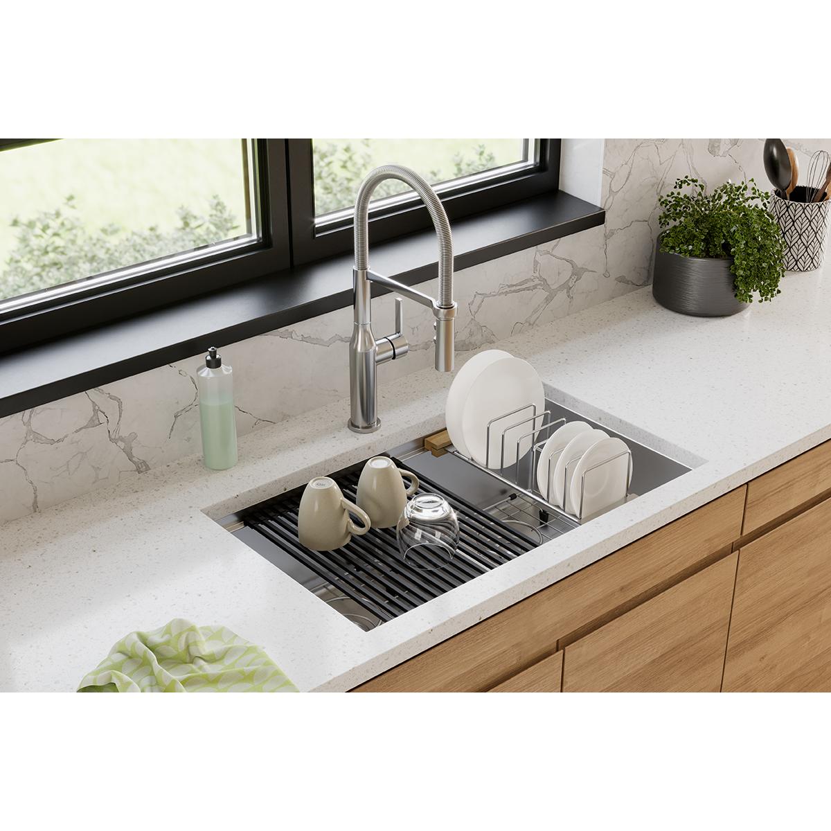 Stainless steel double bowl workstation sink with black divider, grate accessory, and chrome faucet installed in white counte