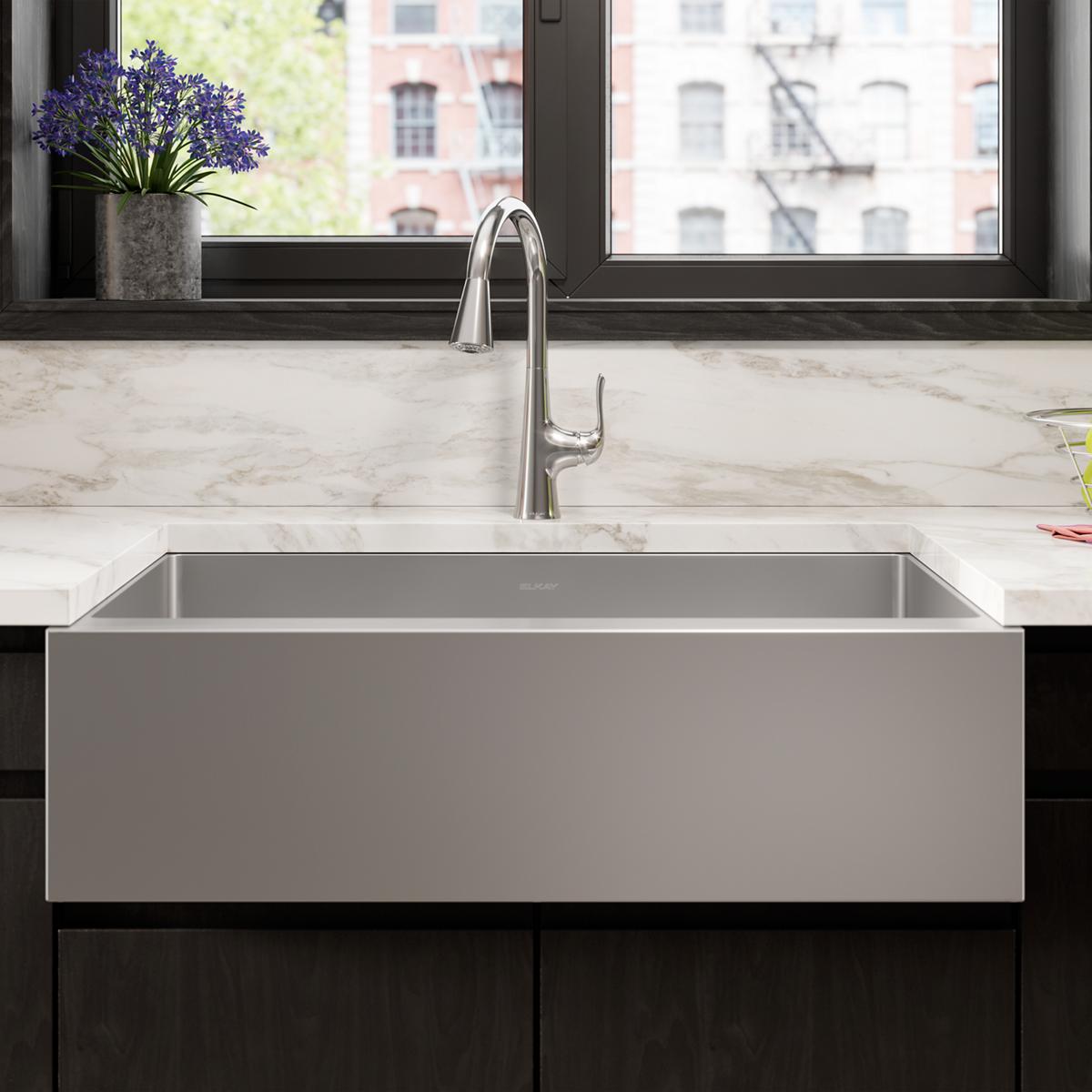 Stainless steel double bowl farmhouse sink with divider and chrome faucet installed in marble countertop.