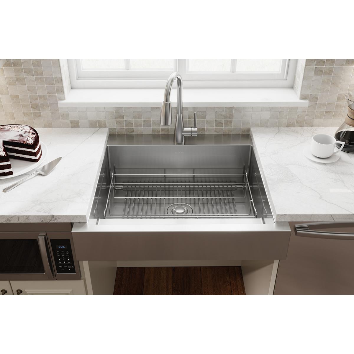 Stainless steel sink grid with parallel ridges positioned in farmhouse-style kitchen sink basin.