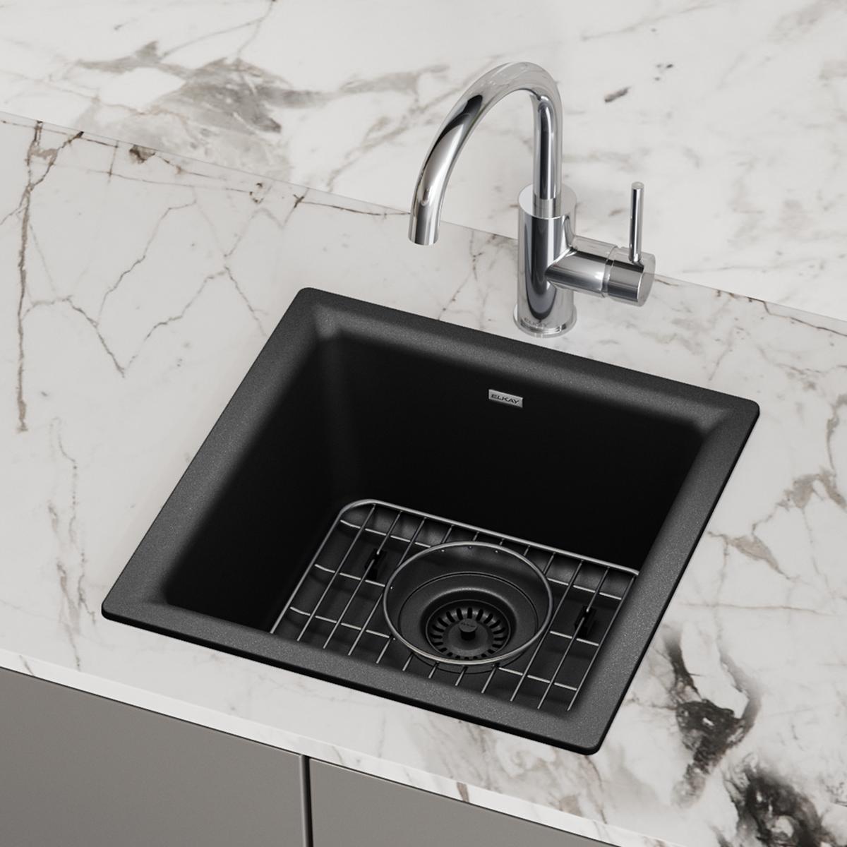Black quartz square bar sink with chrome faucet and grid strainer installed in marble countertop.