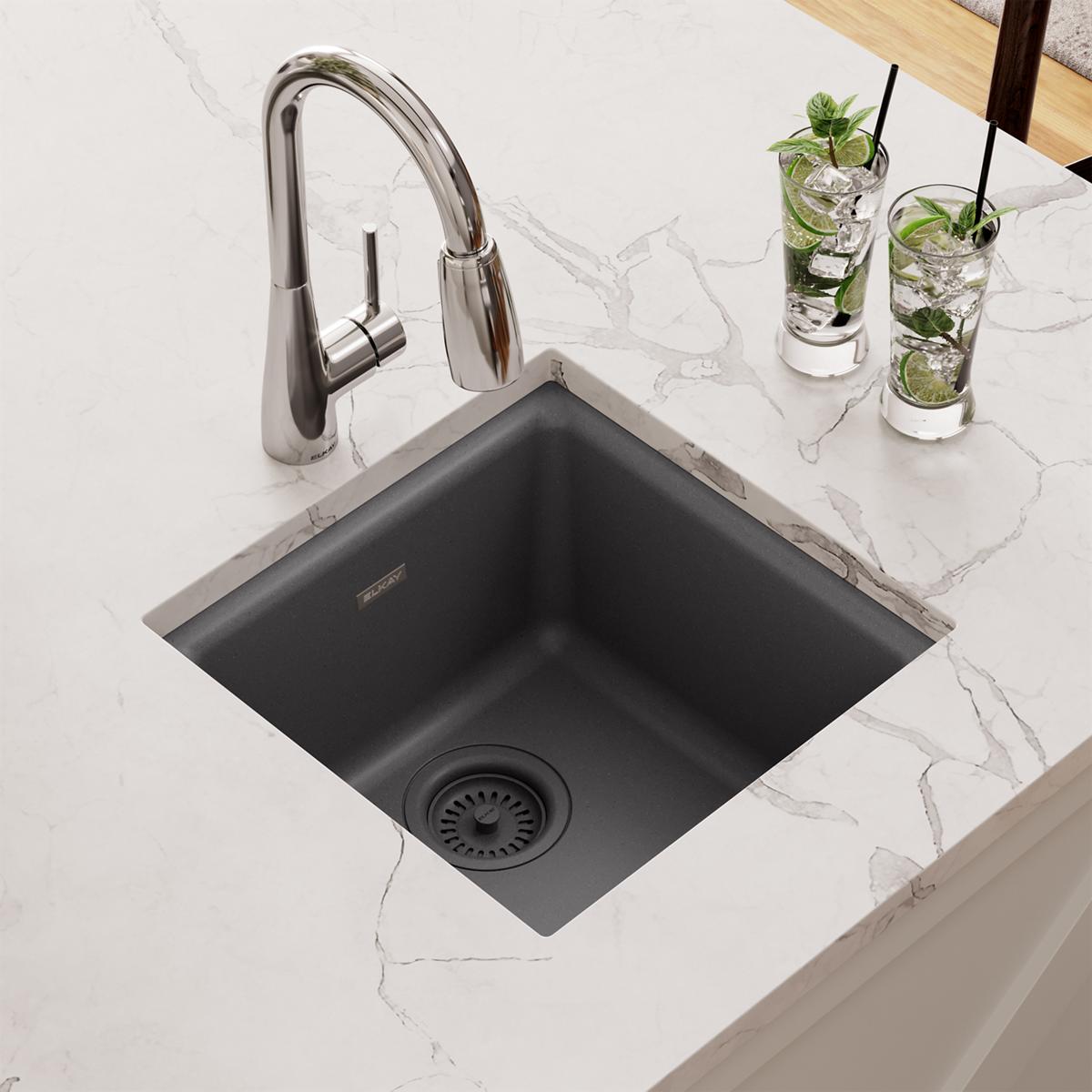 Dusk gray quartz bar sink with single bowl, chrome pull-down faucet, and strainer basket in marble countertop.