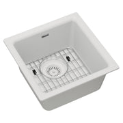 White quartz single bowl bar sink with stainless steel bottom grid and circular drain strainer.
