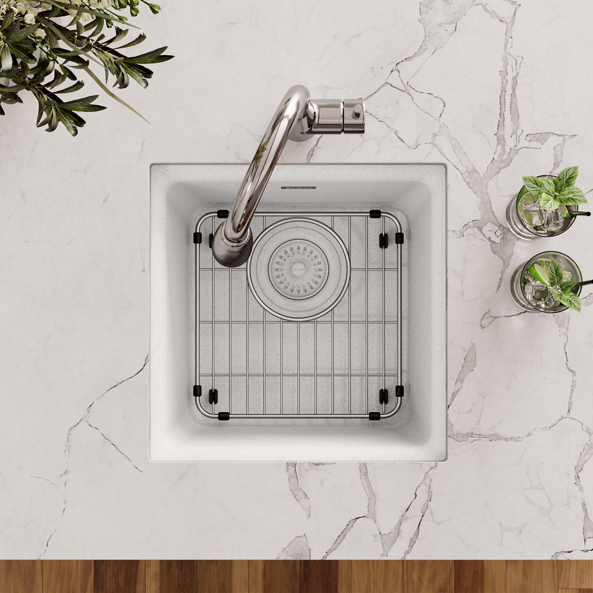 Stainless steel sink grid with vertical slat pattern and black rubber feet placed in white kitchen sink.