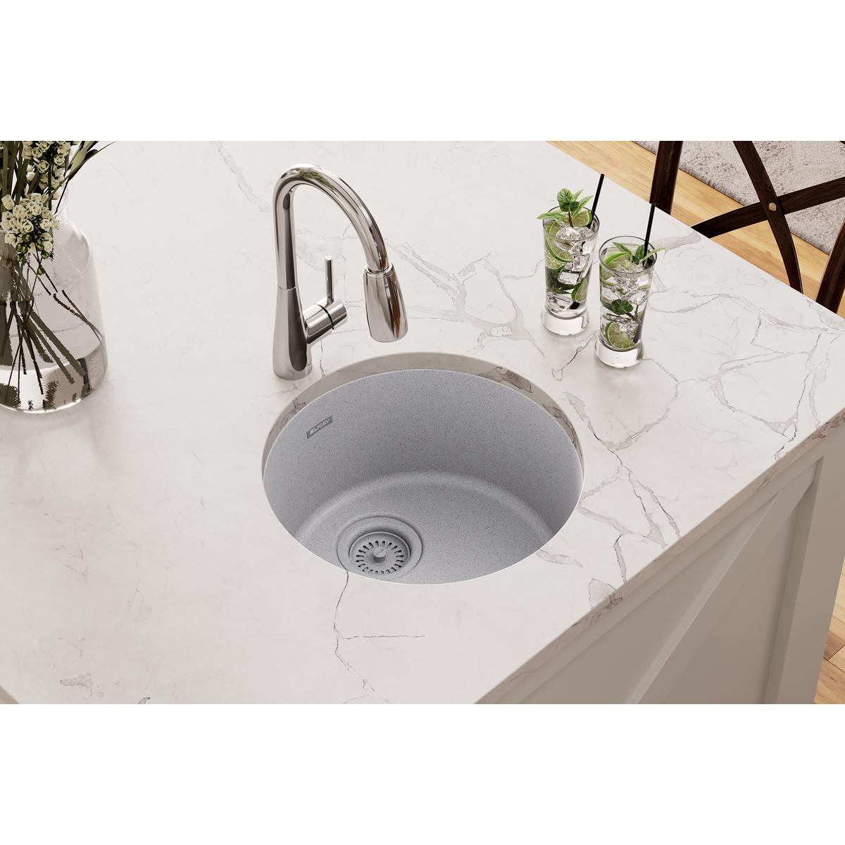 Greystone quartz single bowl bar sink mounted in white countertop with chrome pull-down faucet.