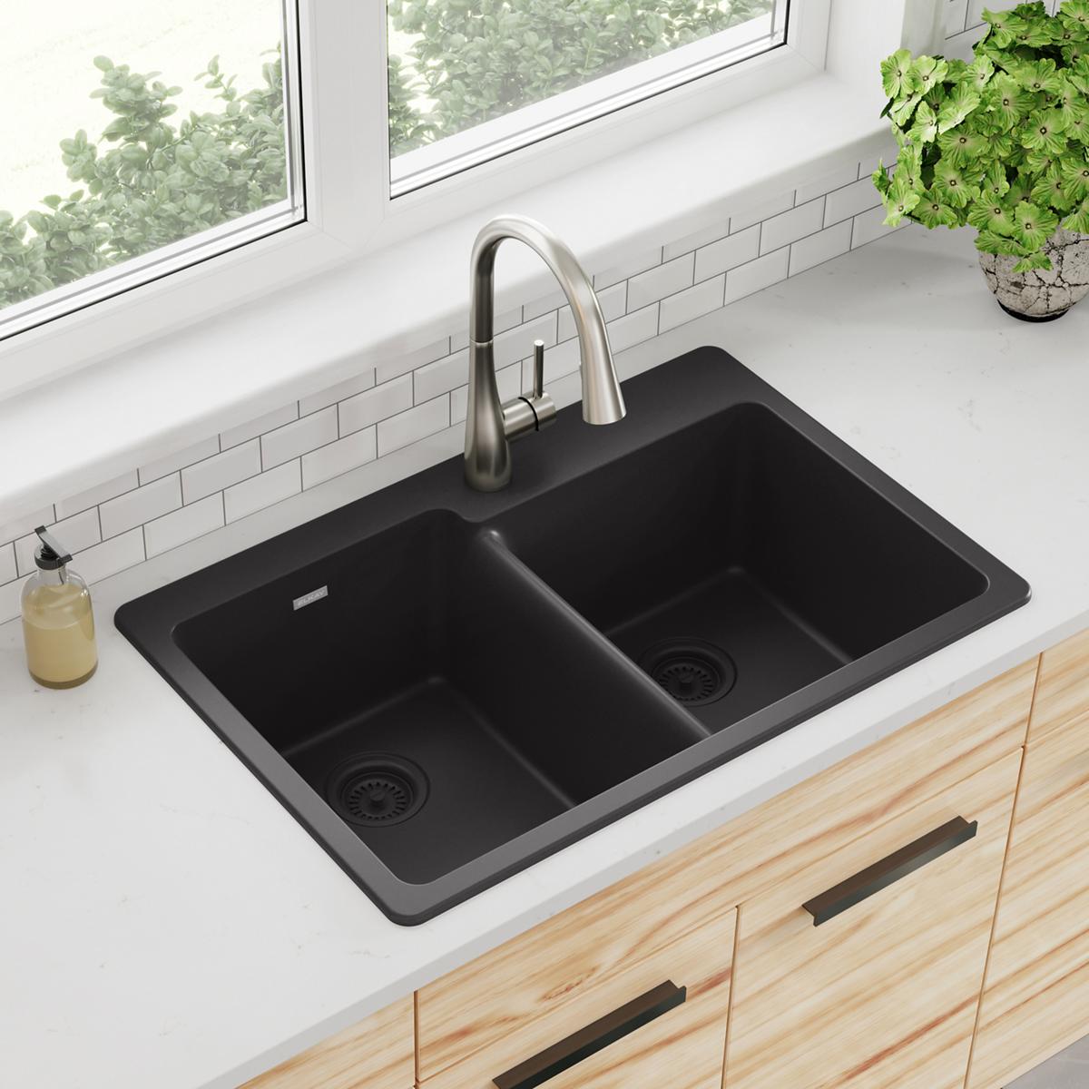 Black quartz double bowl drop-in sink with offset basins and integrated drains installed in white countertop.