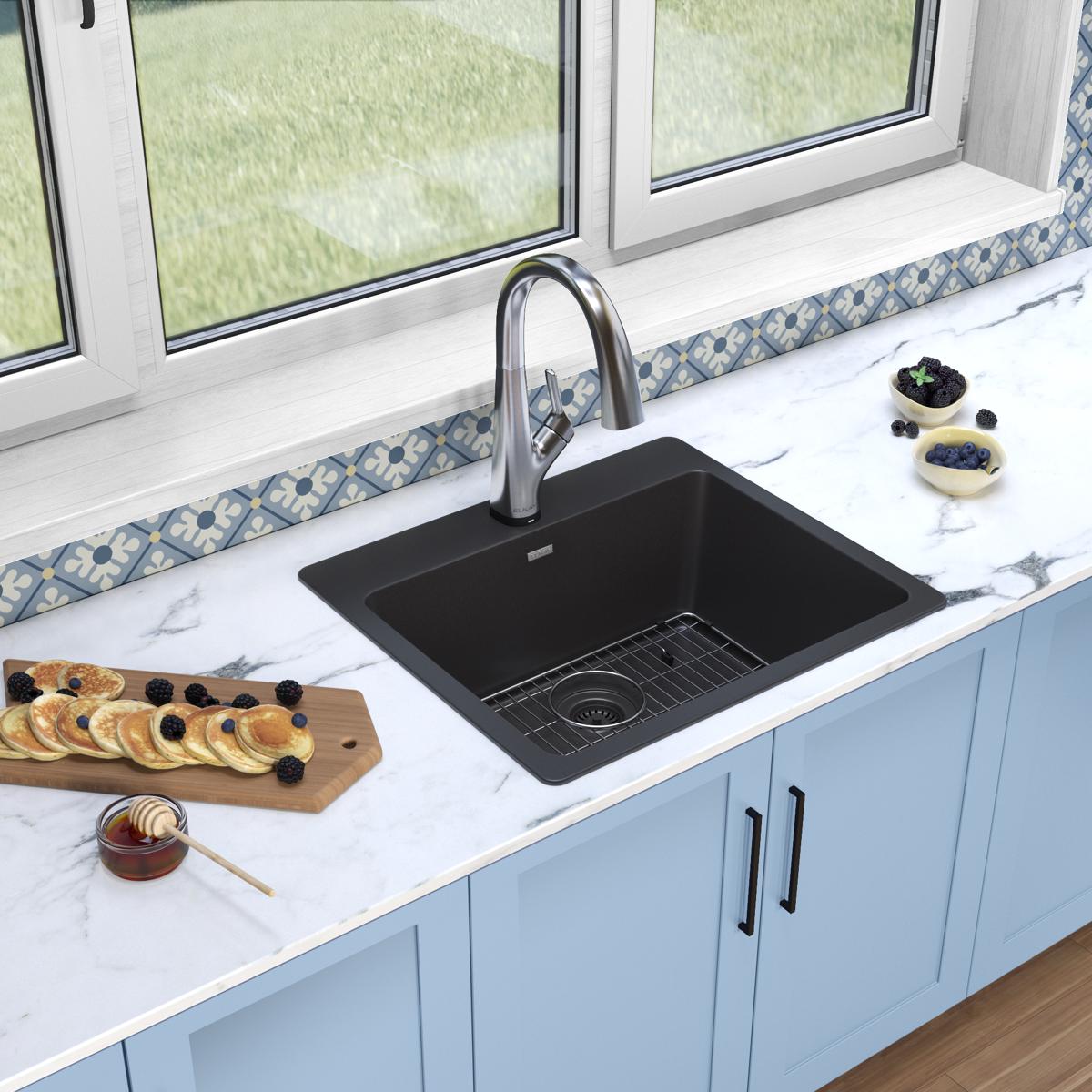 Black quartz drop-in kitchen sink with single bowl and stainless steel pull-down faucet installed in white marble countertop.