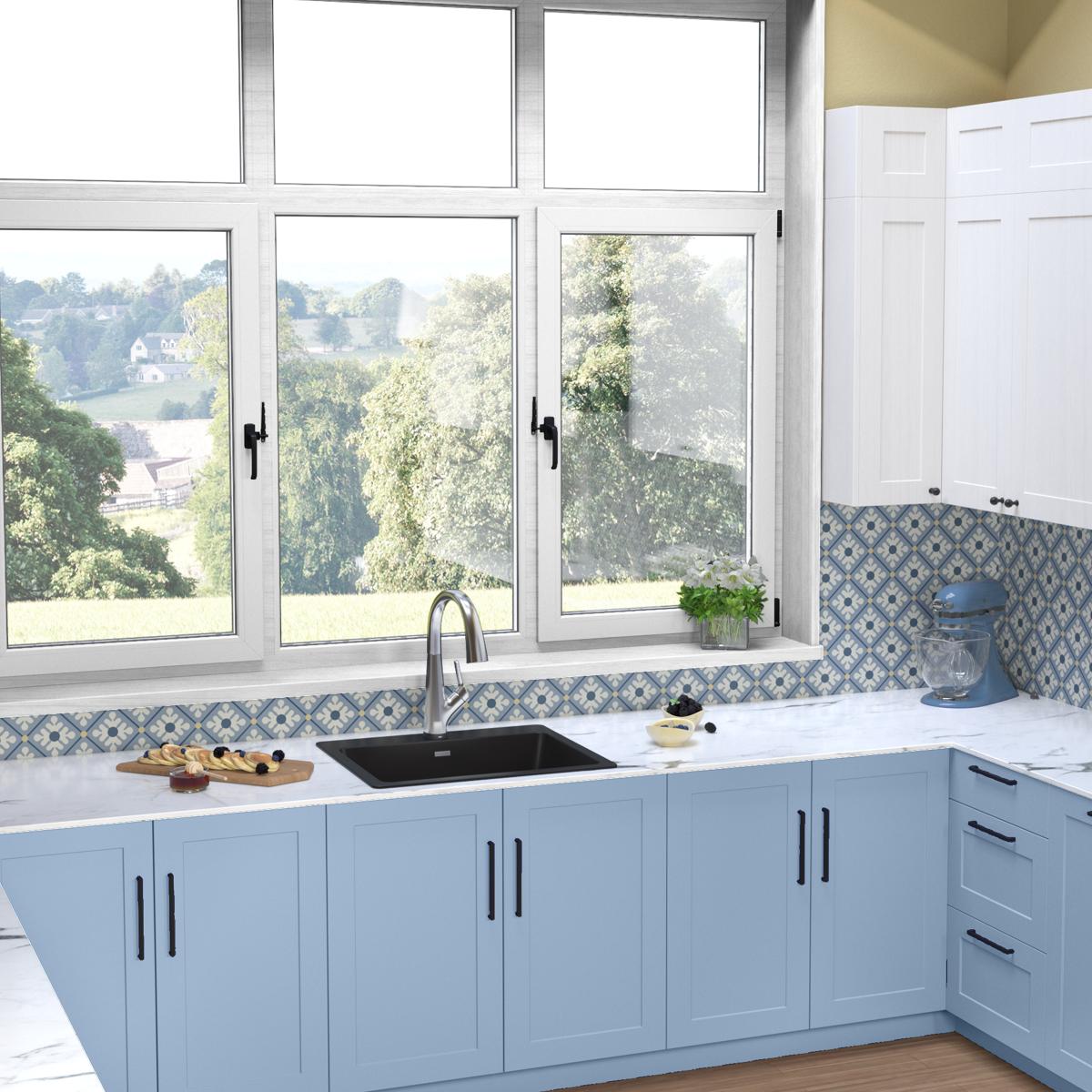 Black quartz single bowl drop-in sink with filtered faucet installed in light blue kitchen cabinets beneath windows.