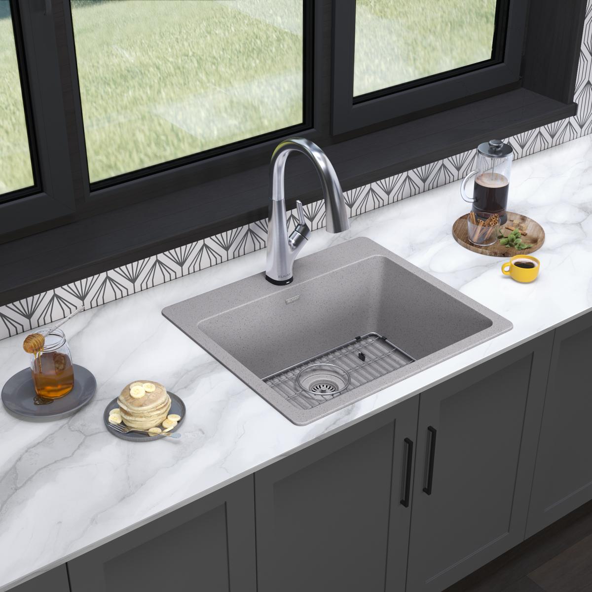 Greystone quartz drop-in sink with single bowl and chrome filtered faucet installed in white marble countertop.