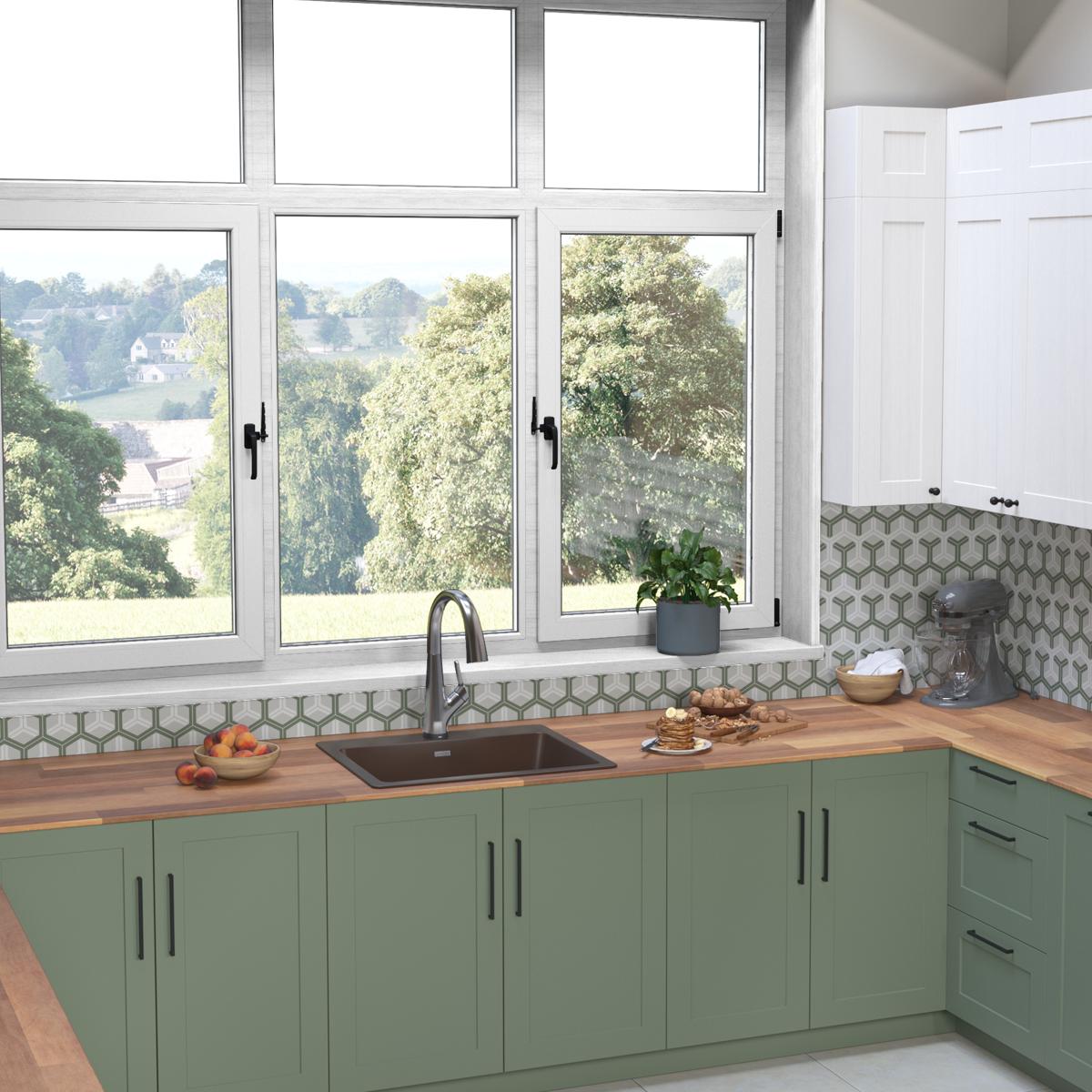 Mocha quartz drop-in sink with black filtered faucet installed in green kitchen cabinetry with wood countertop.