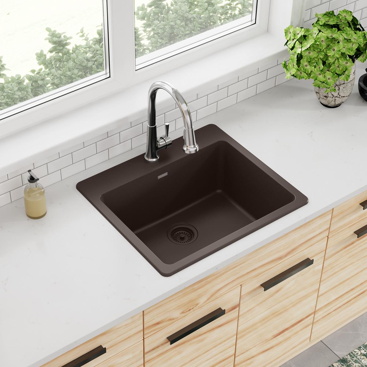 Mocha quartz drop-in sink with single bowl, chrome faucet, and drain strainer installed in white countertop.