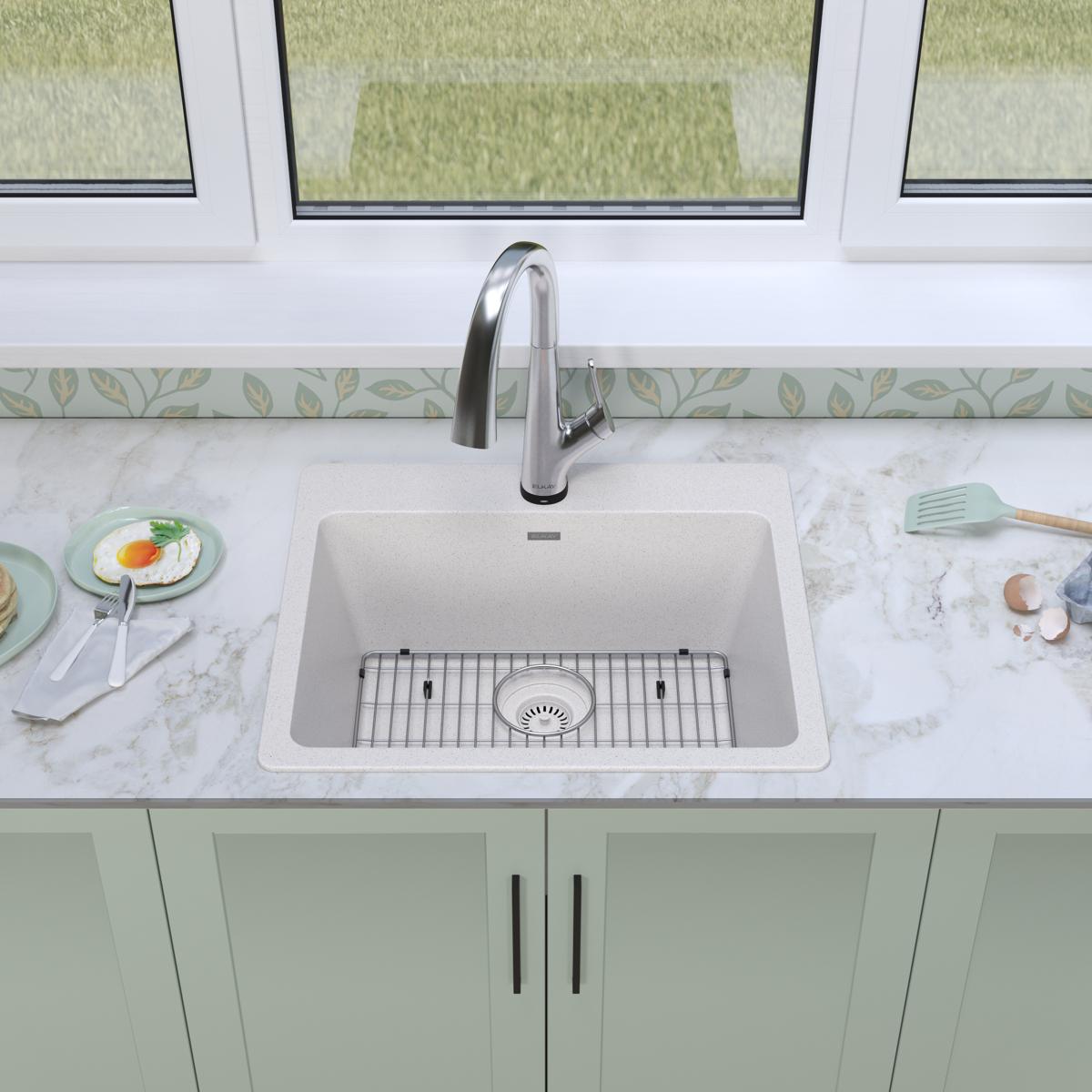White quartz single bowl drop-in sink with stainless steel filtered faucet and matching grid strainer installed in marble cou