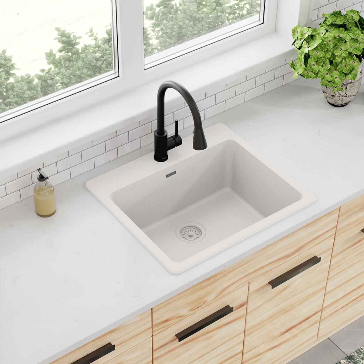 White quartz single bowl drop-in sink with black pull-down faucet installed in white countertop.