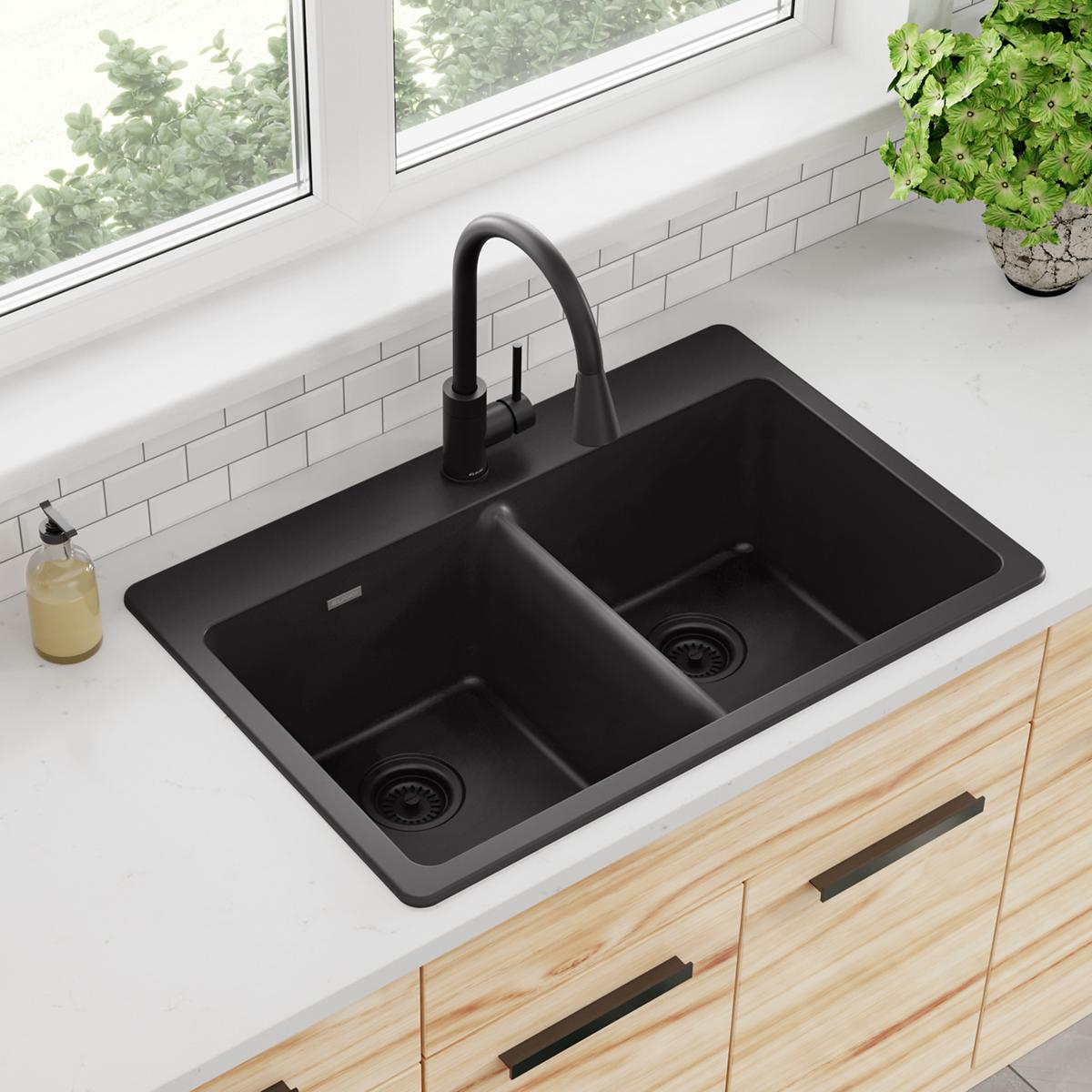 Black quartz double bowl drop-in sink with black faucet installed in white countertop.