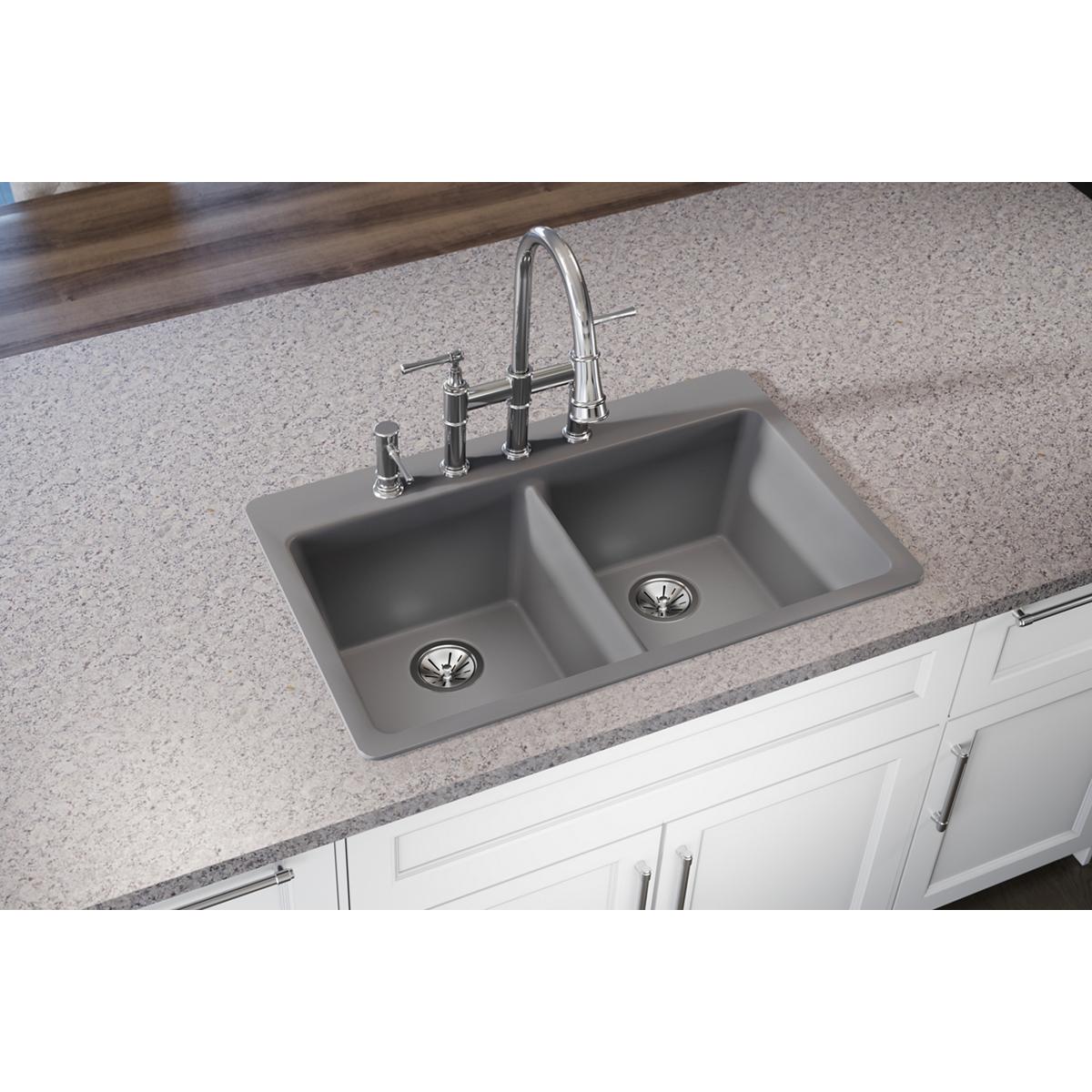 Greystone quartz double bowl drop-in sink with two equal compartments and chrome faucet installed in countertop.