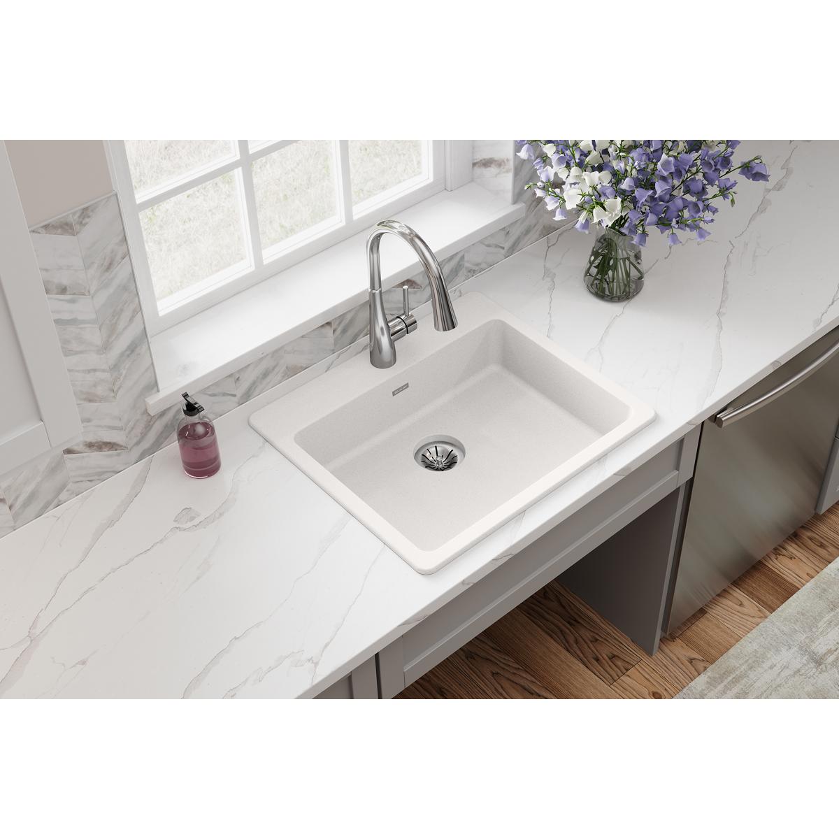 White quartz drop-in sink with single bowl and drain installed in marble countertop with chrome faucet.