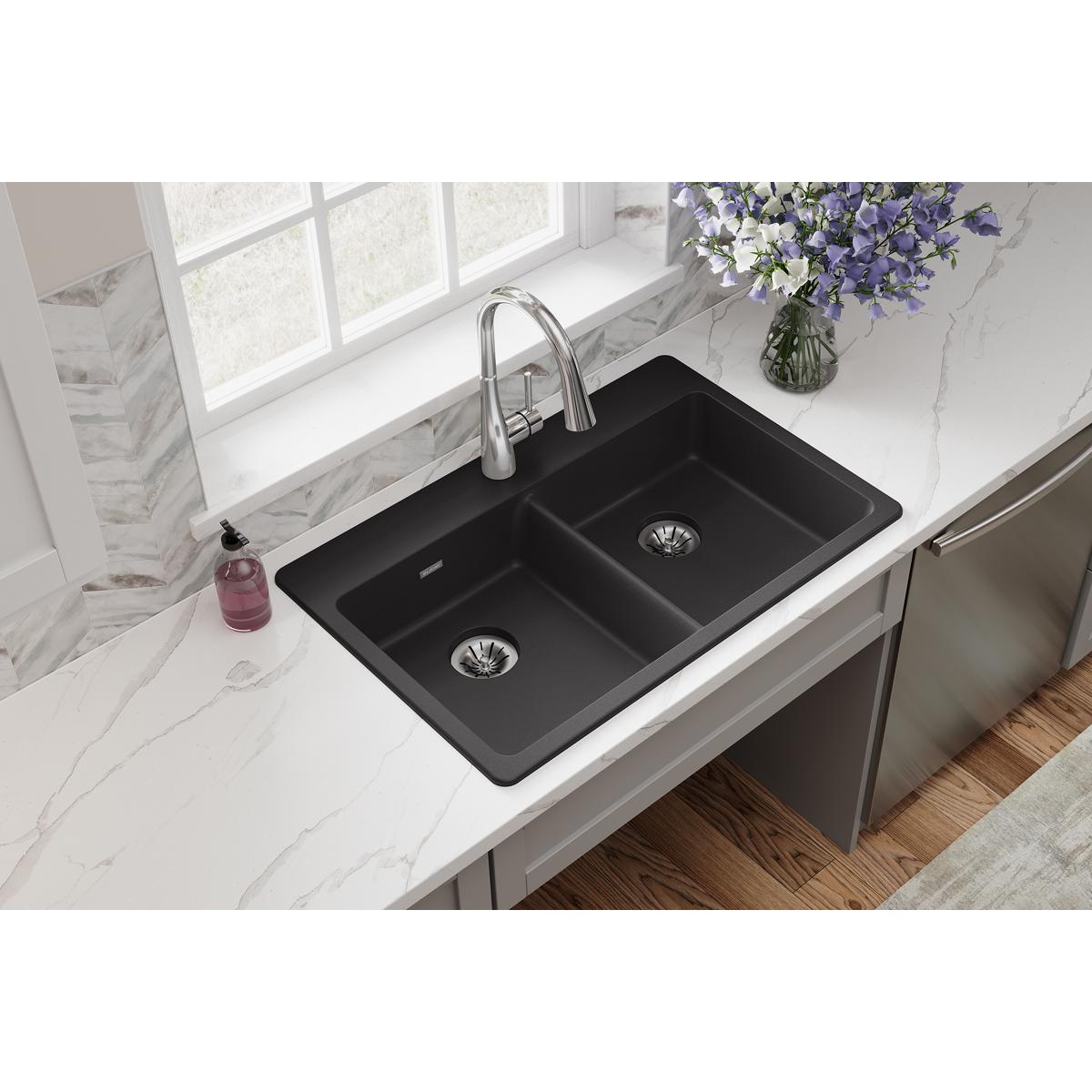 Black quartz double bowl drop-in sink with chrome faucet installed in white marble countertop.