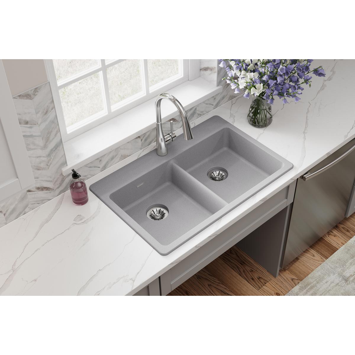 Greystone quartz double bowl drop-in sink installed in white countertop with chrome faucet and drain strainers.