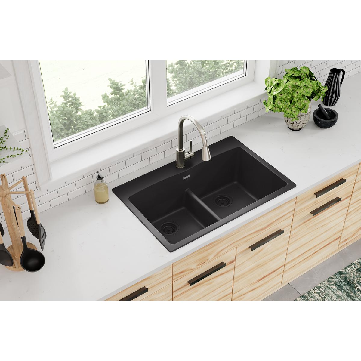 Black quartz drop-in sink with two equal bowls separated by center divider, installed in white countertop.