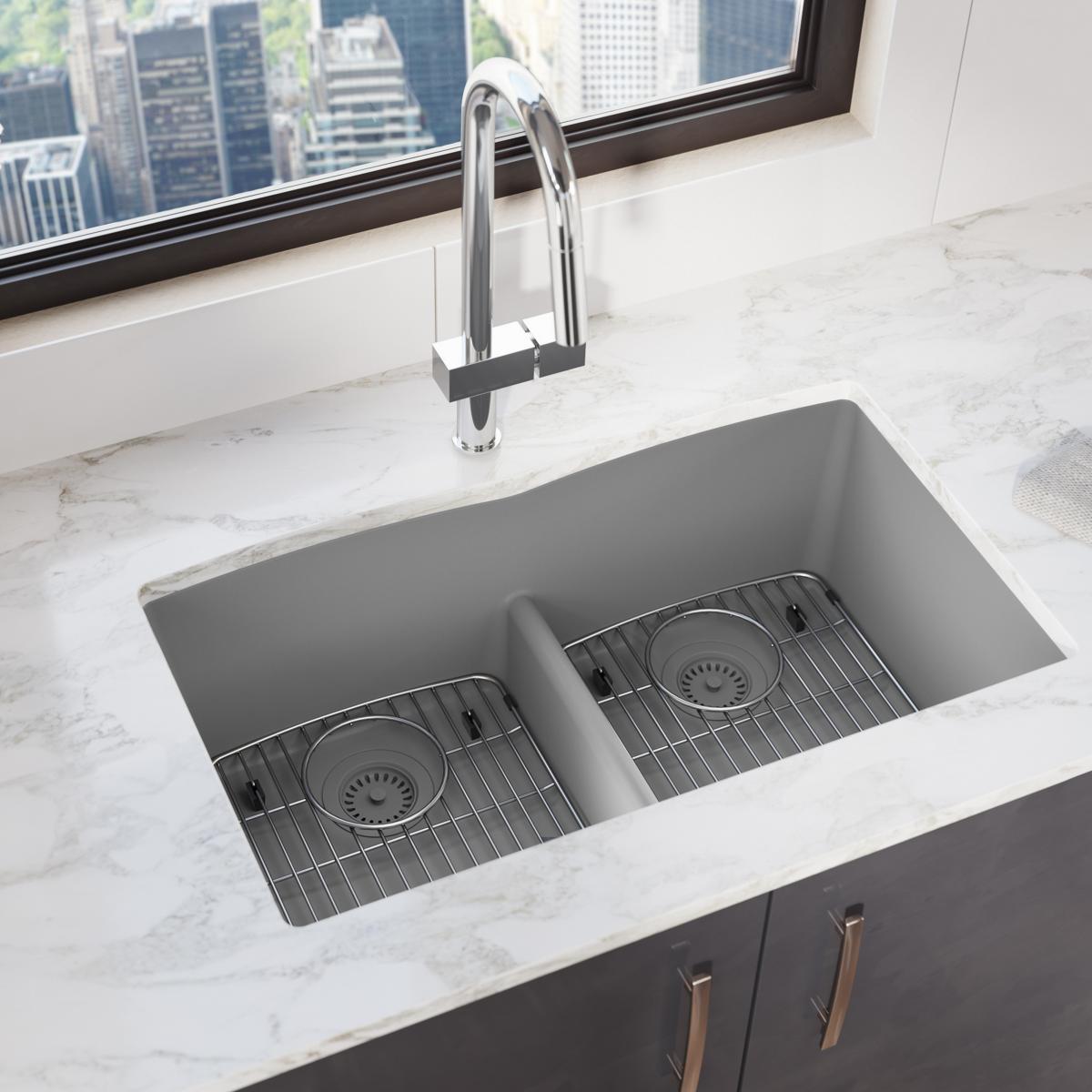 Greystone quartz double bowl undermount sink with stainless steel grid inserts and chrome faucet installed in marble countert