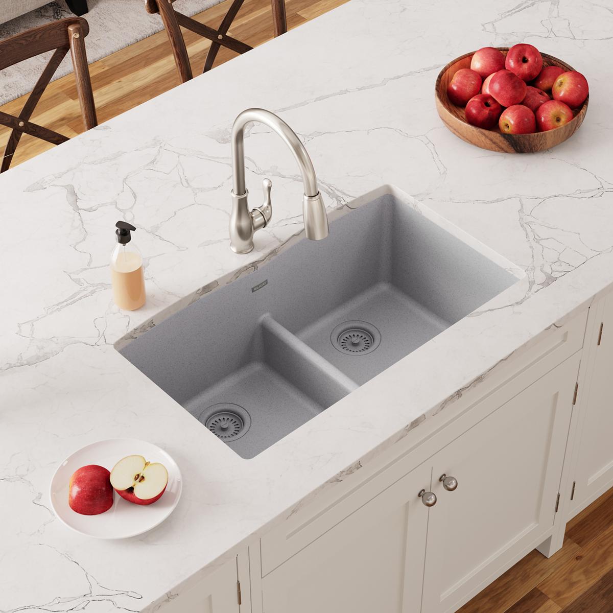 Greystone quartz double bowl undermount sink with stainless steel faucet installed in white marble countertop.