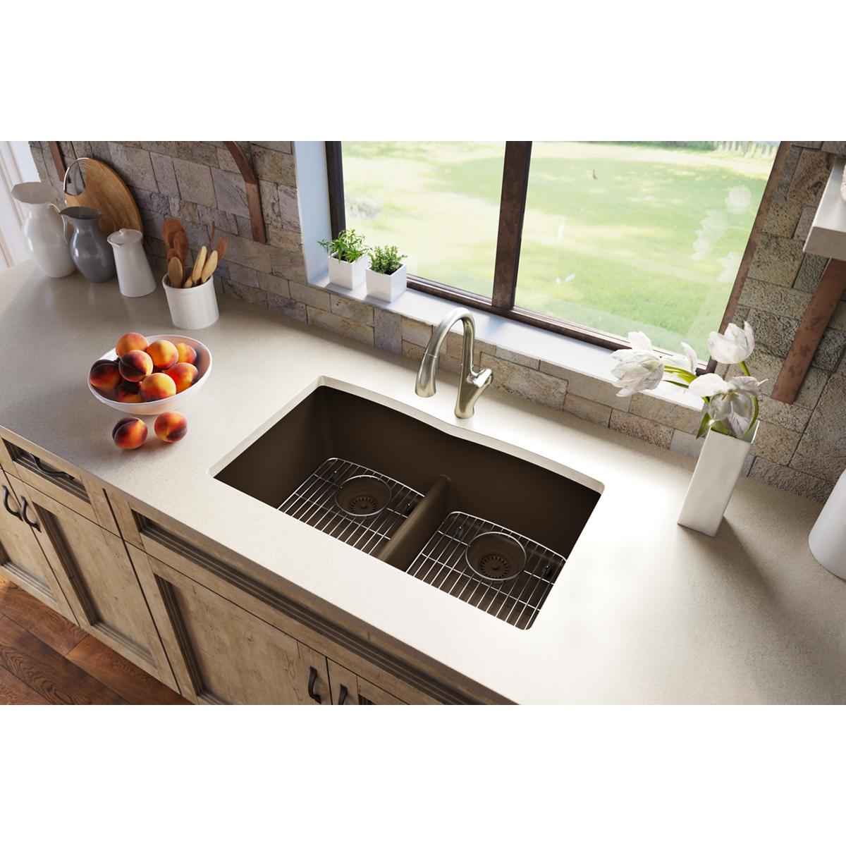 Mocha quartz double bowl undermount sink installed in white countertop with two grid inserts and chrome faucet.