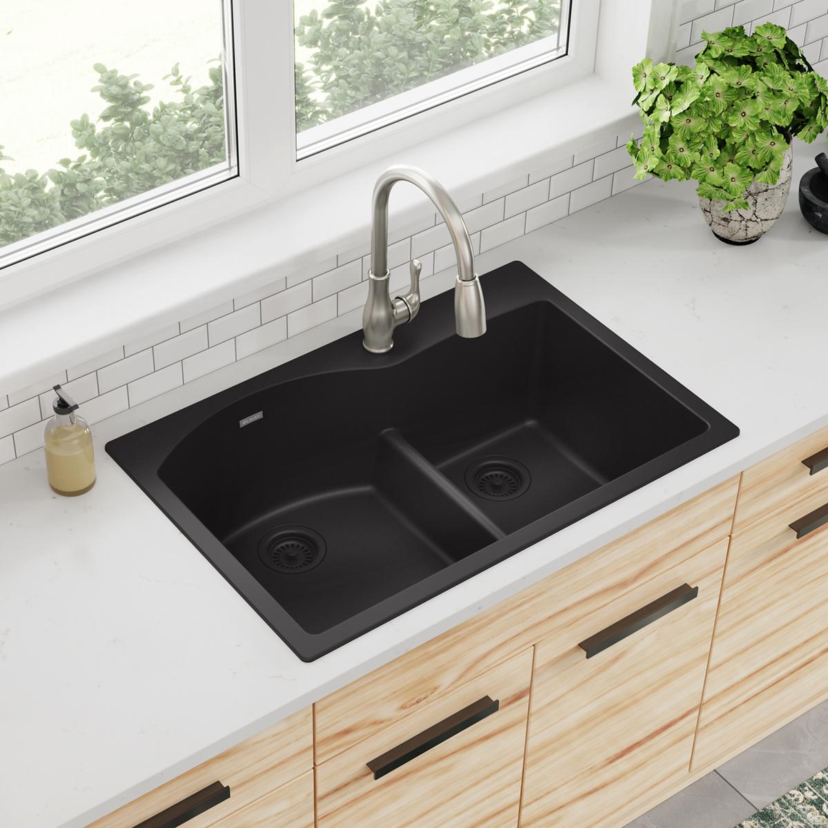 Black quartz double bowl drop-in sink with stainless steel faucet installed in white countertop.
