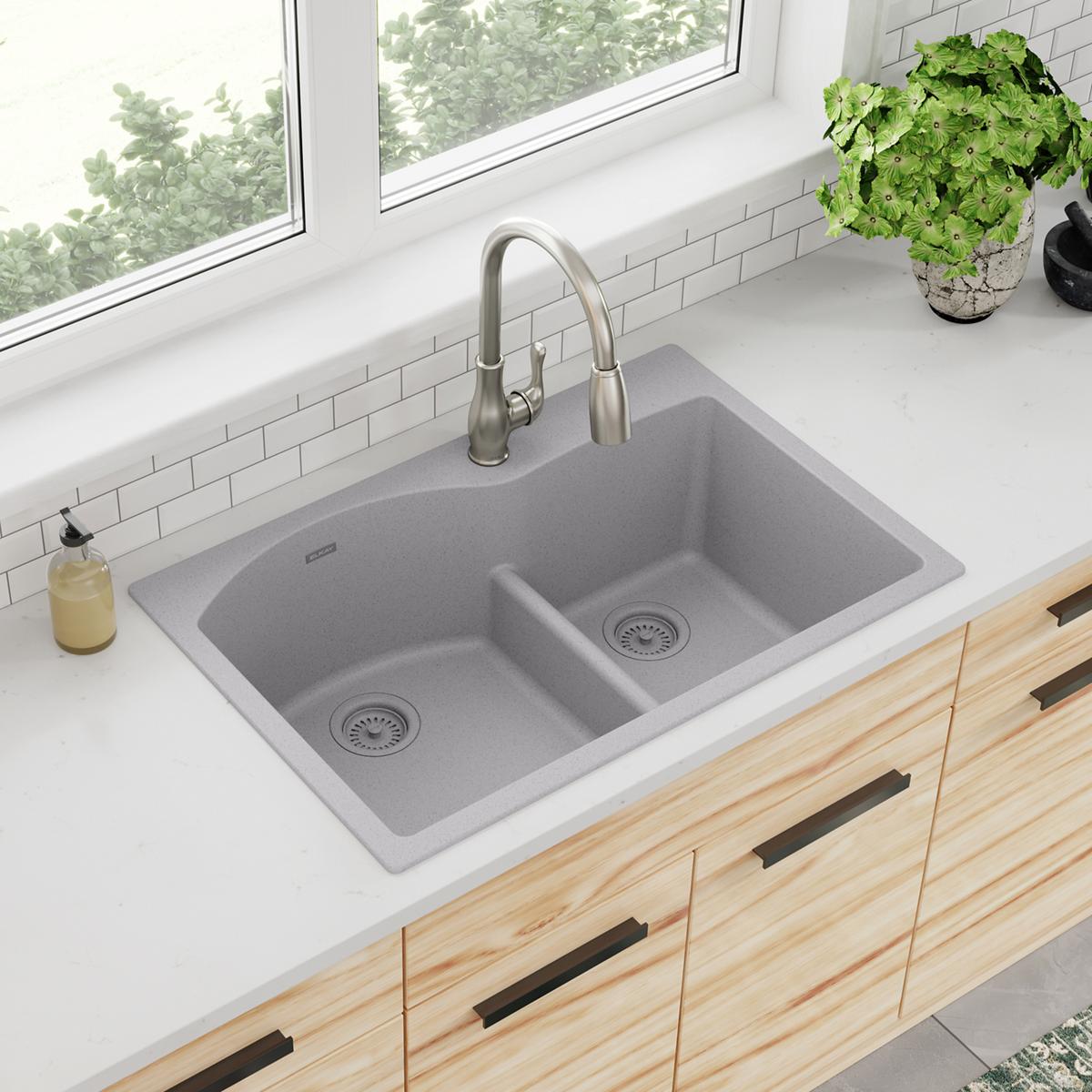 Greystone quartz double bowl drop-in sink with divider, stainless steel faucet, and drain strainers installed in white counte