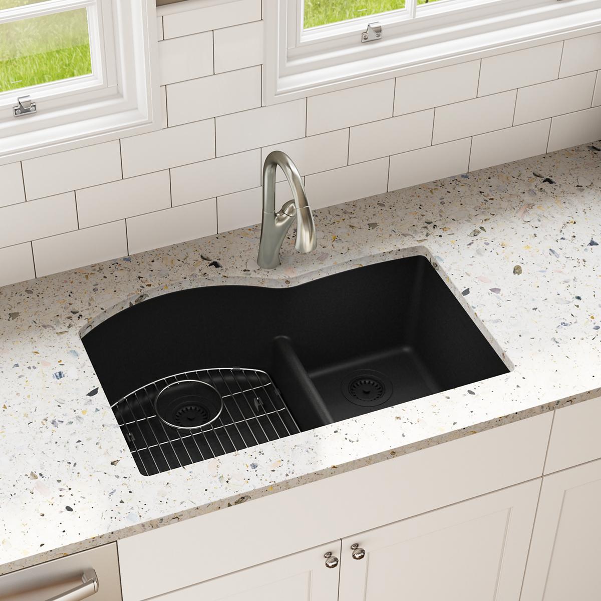Black quartz double bowl undermount sink with offset 60/40 configuration, metal grids, and chrome faucet installed in speckle