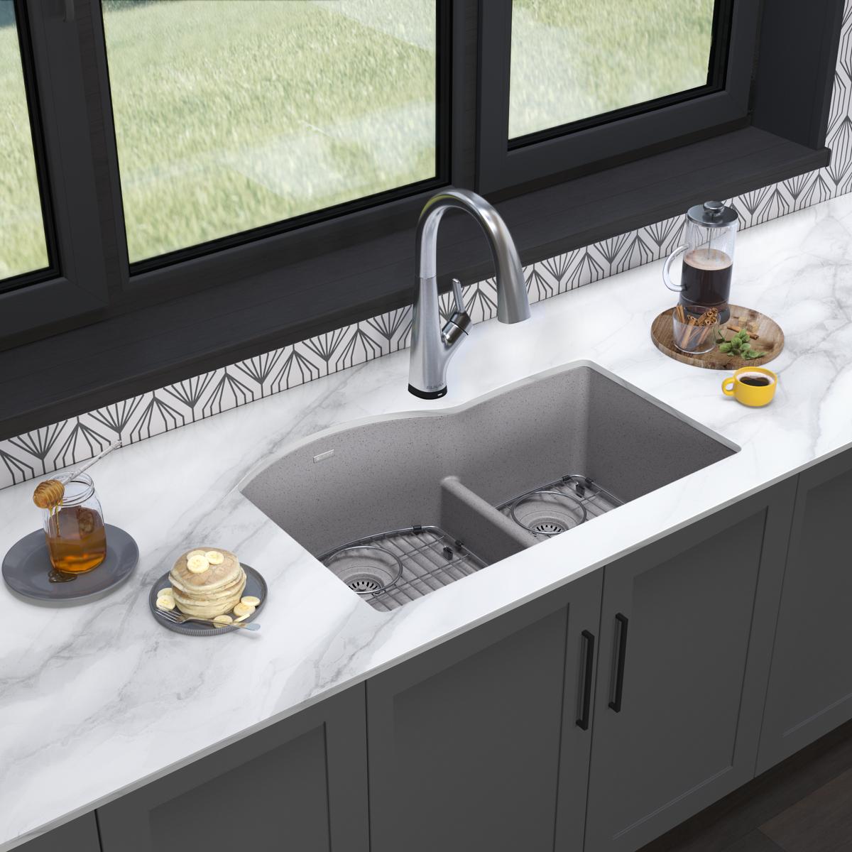 Greystone quartz double bowl undermount sink with offset 60/40 compartments, chrome faucet, and basin grids installed in marb