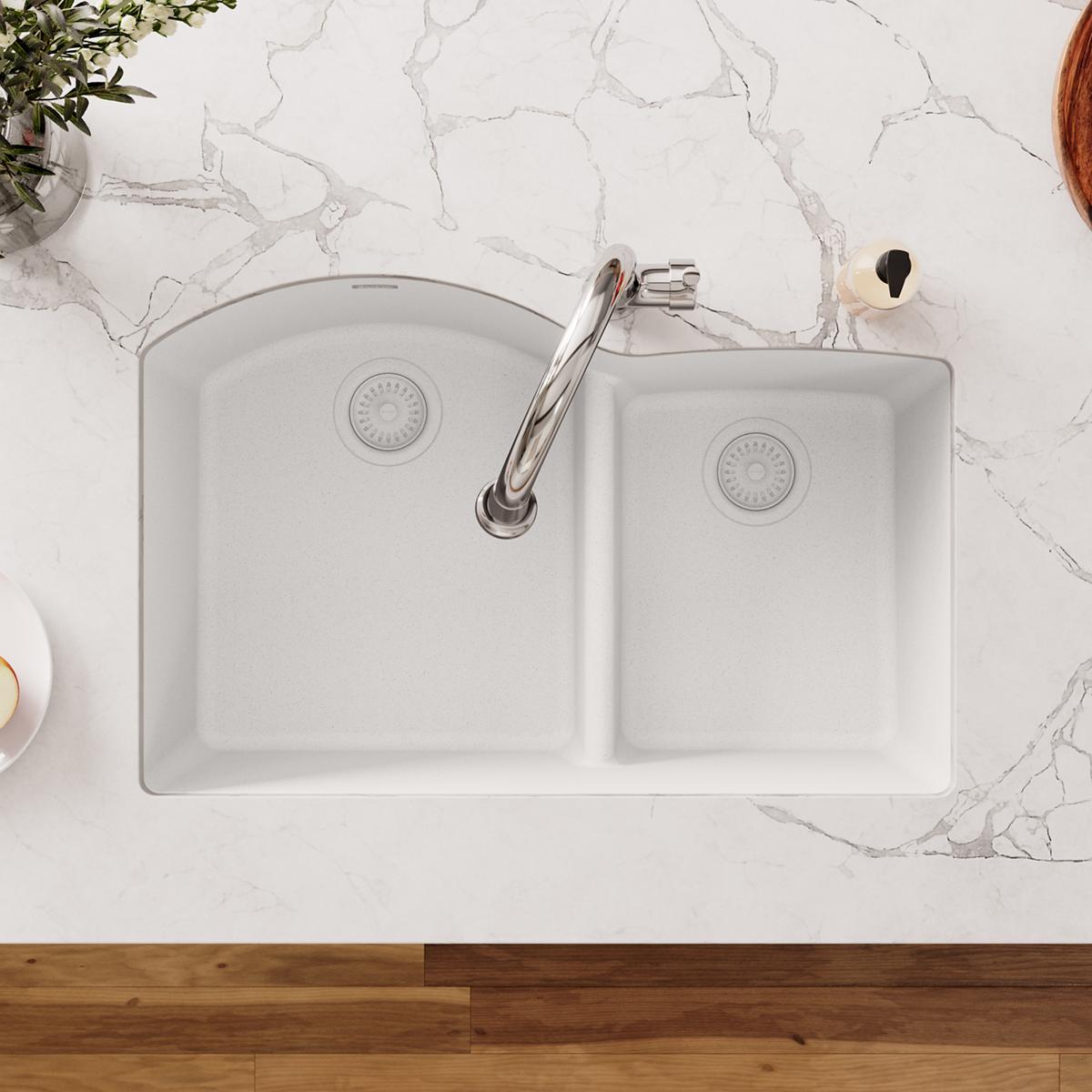 White polymer sink strainer flange with removable basket and rubber stopper installed in double basin sink.