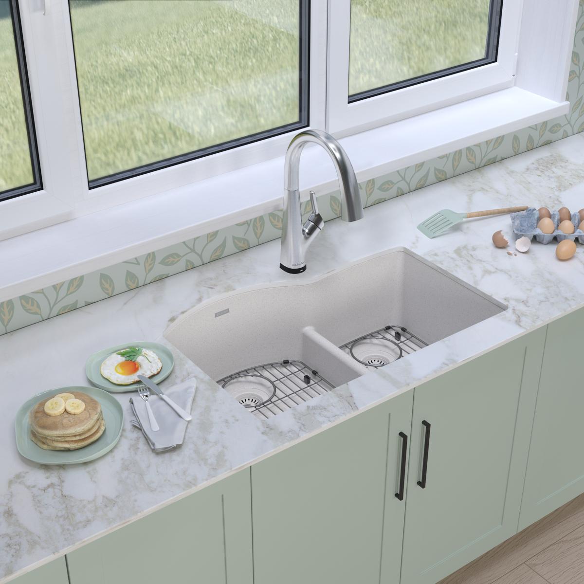 White quartz undermount double bowl sink with offset compartments, stainless steel faucet, and included drains and divider.