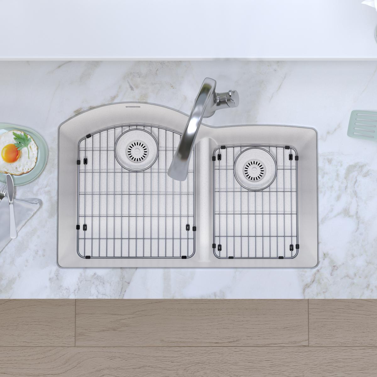 White quartz double bowl undermount sink with offset basins, metal grid inserts, and chrome faucet with divider on marble cou