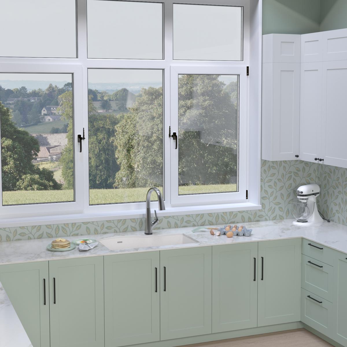 White quartz double bowl undermount sink with filtered faucet installed in green kitchen cabinetry beneath windows.