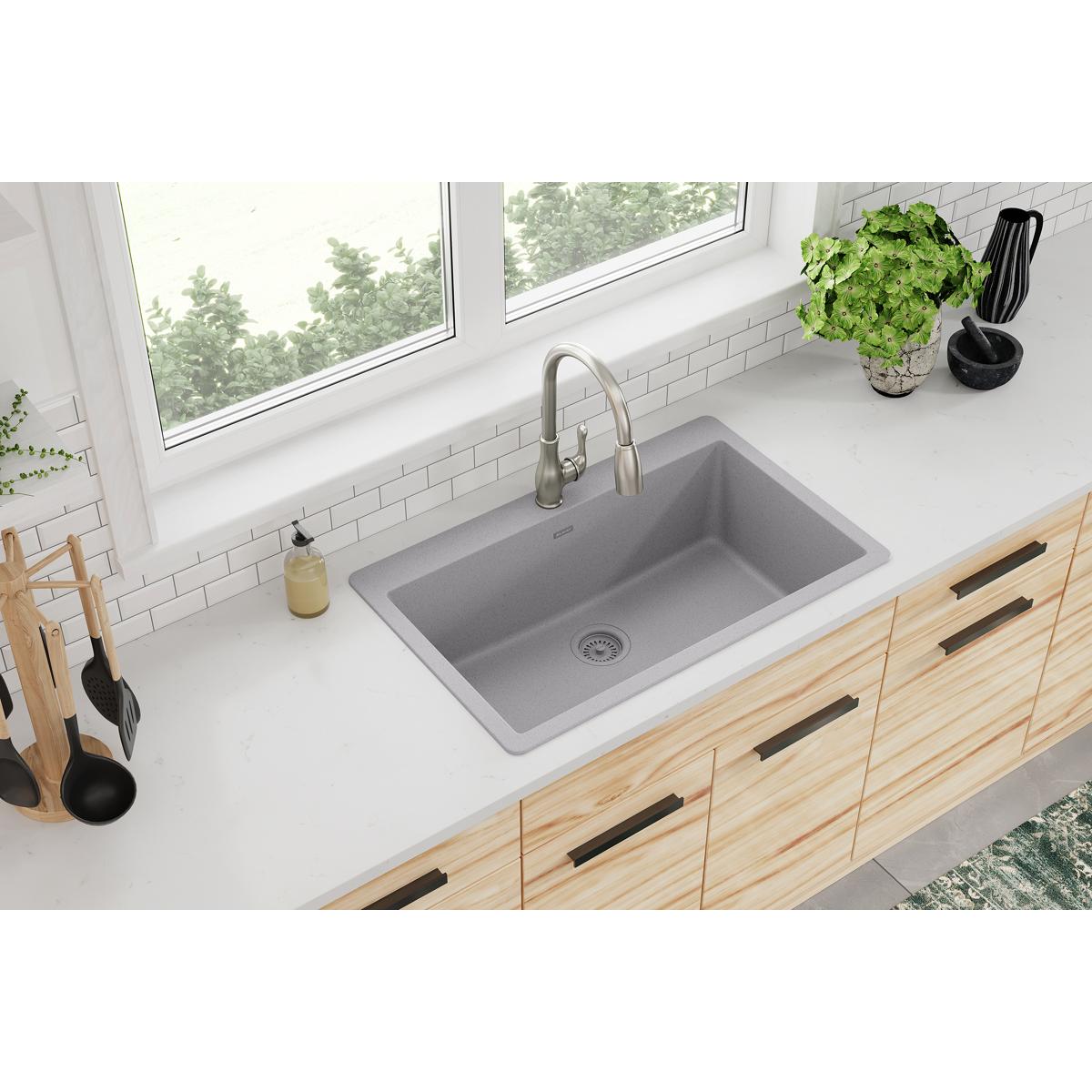 Greystone quartz single-bowl drop-in sink installed in white countertop with stainless steel faucet.