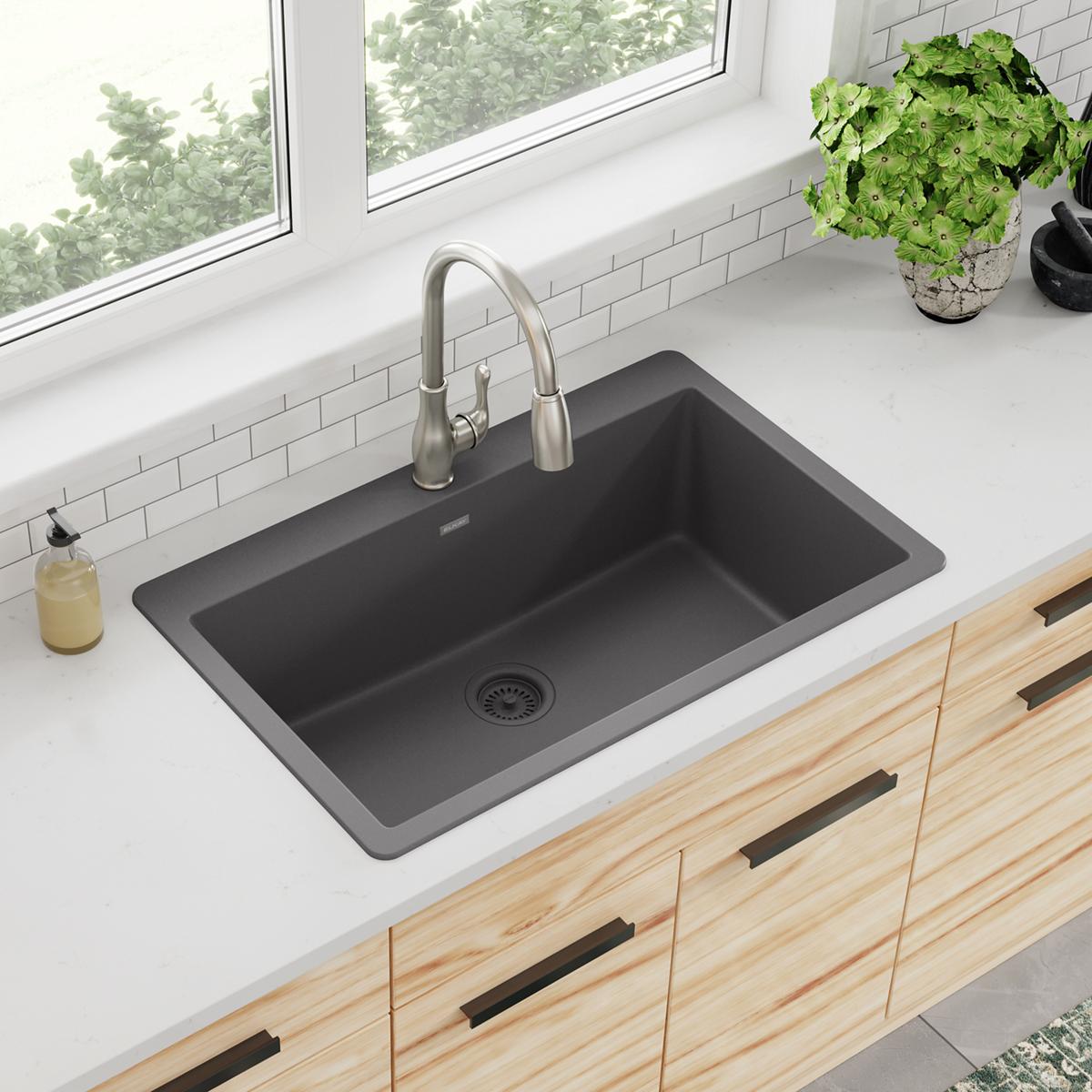 Dusk gray single bowl drop-in sink with stainless steel faucet installed in white countertop.