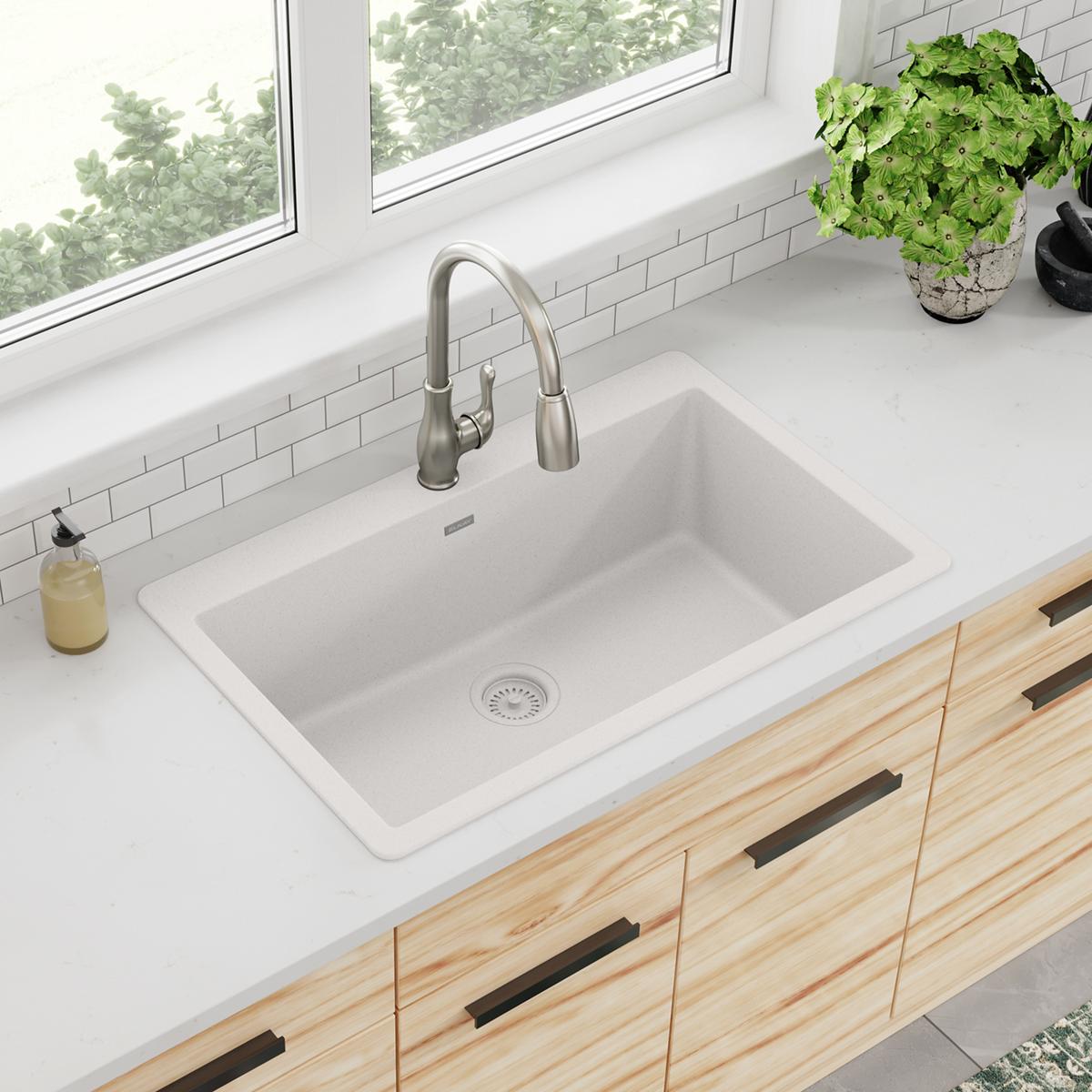 White quartz single bowl drop-in sink with stainless steel faucet installed in kitchen counter.