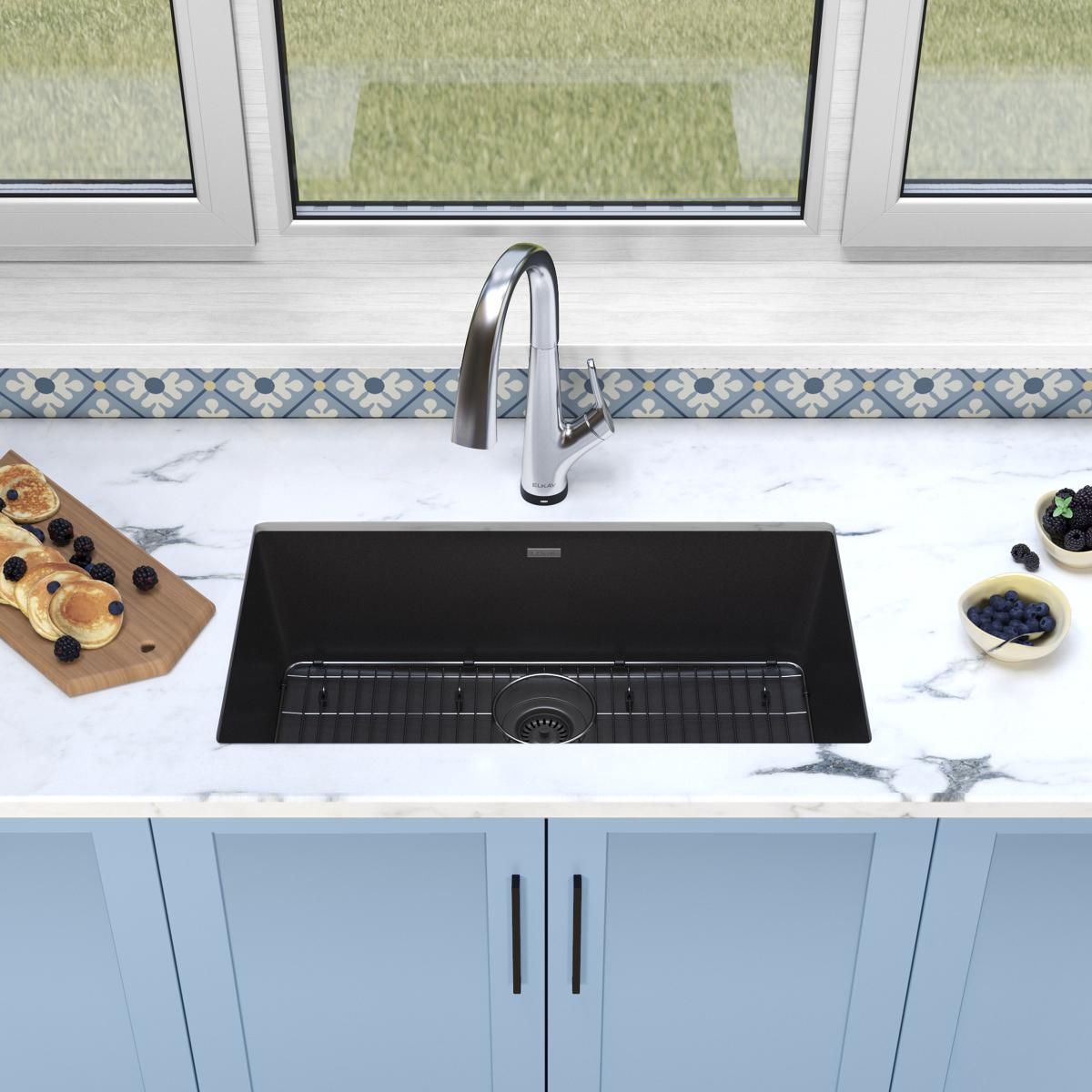 Black undermount kitchen sink with single bowl and arched chrome filtered faucet installed in marble countertop.