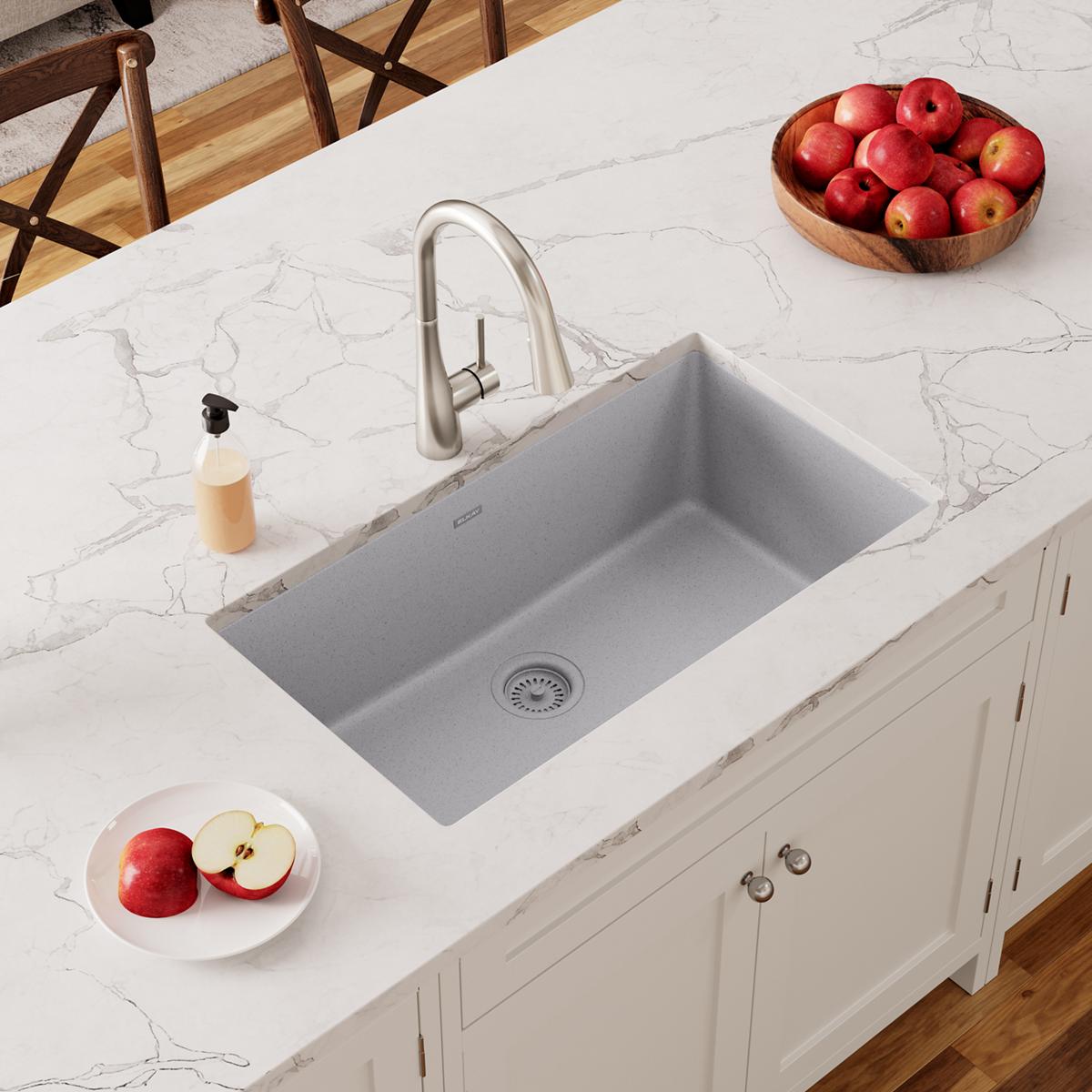 Greystone quartz undermount sink installed in white marble countertop with stainless steel faucet.