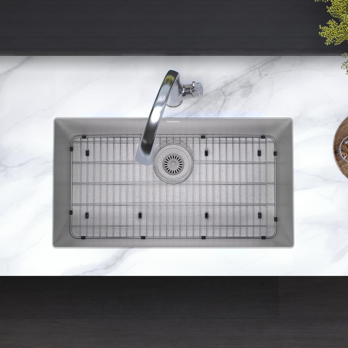 Greystone quartz single bowl undermount sink with stainless steel faucet, grid, and drain strainer installed in marble counte