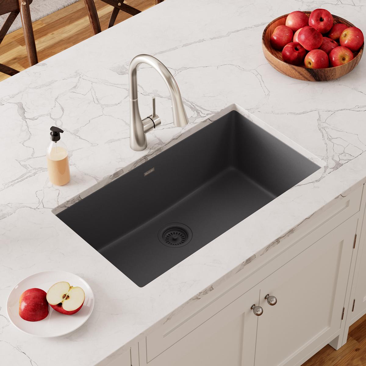 Dark gray quartz undermount sink with single basin installed in white marble countertop with chrome faucet.